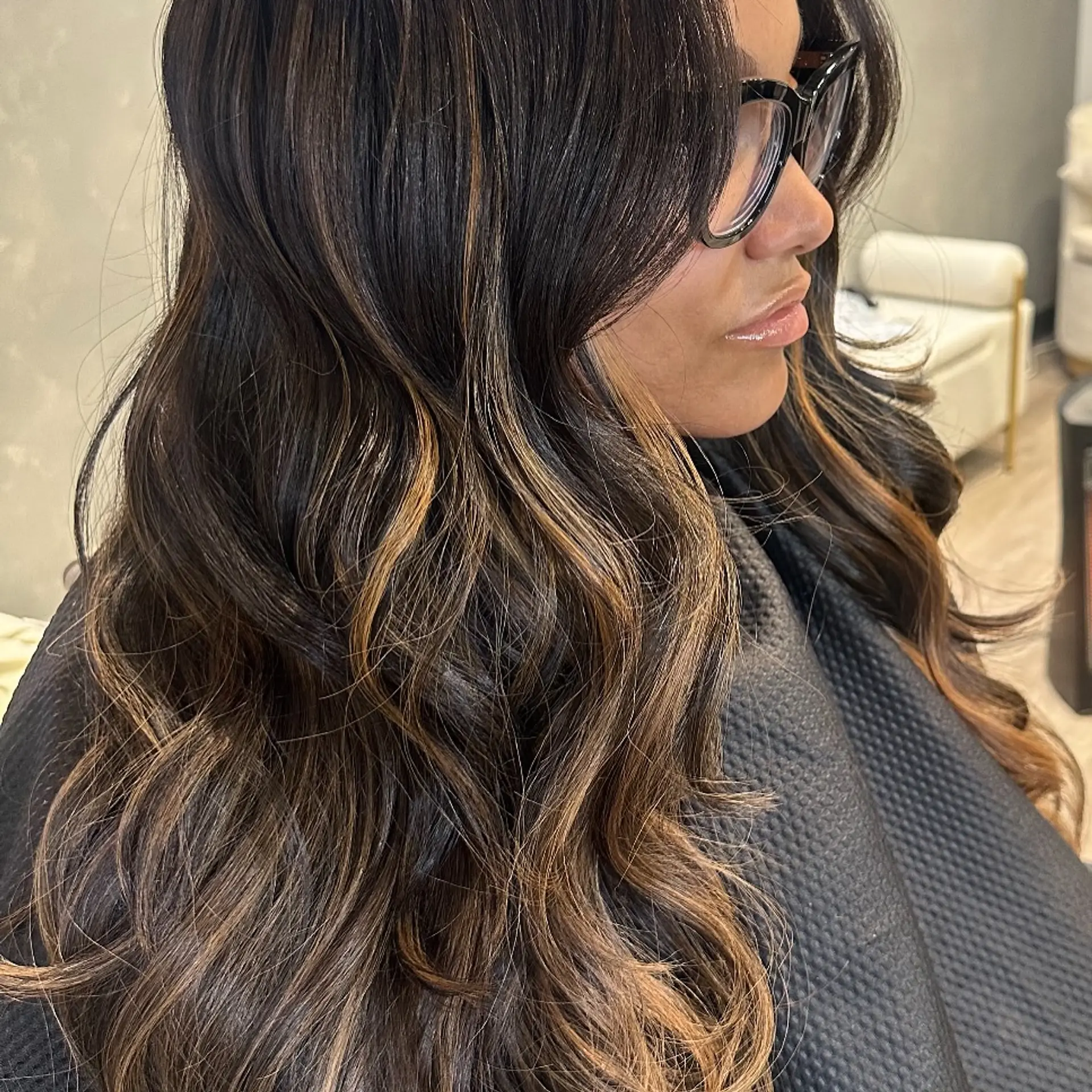 A long, layered hairstyle with waves and balayage highlights. 6