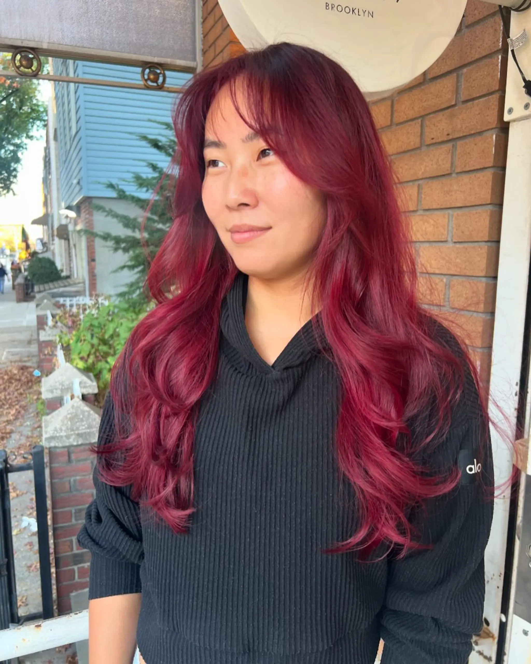 Long, flowing waves with deep red and burgundy tones, featuring soft fringe bangs and textured layers.