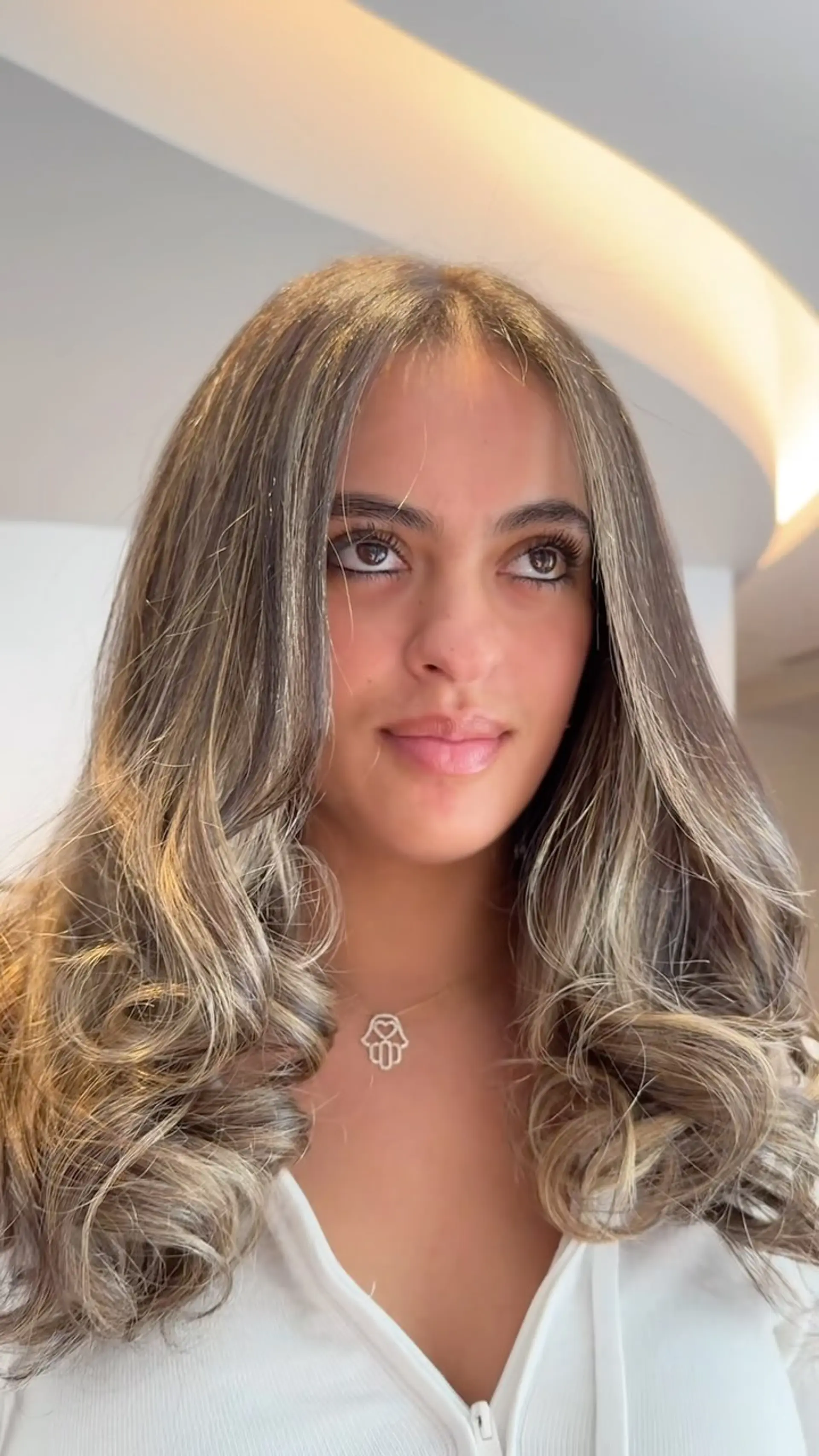Long ash and beige blonde babylights styled into a bouncy, voluminous blowout with curled ends. 1