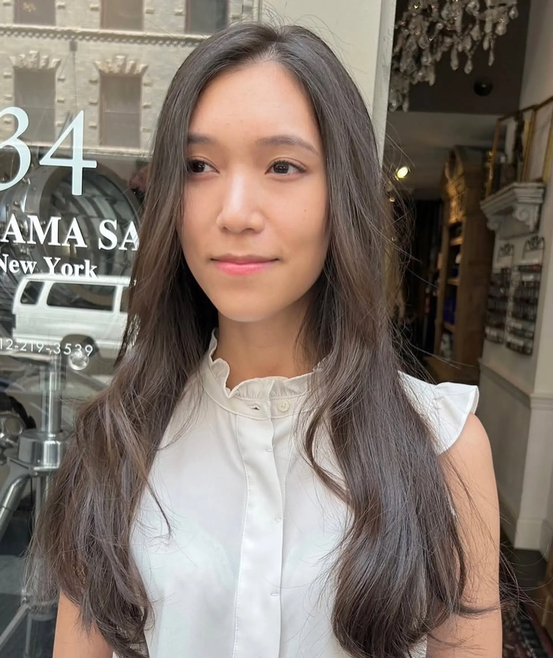 This hairstyle features long, dark brown hair with soft, flowing waves and a center parting, incorporating face-framing layers for a natural, elegant look. 1