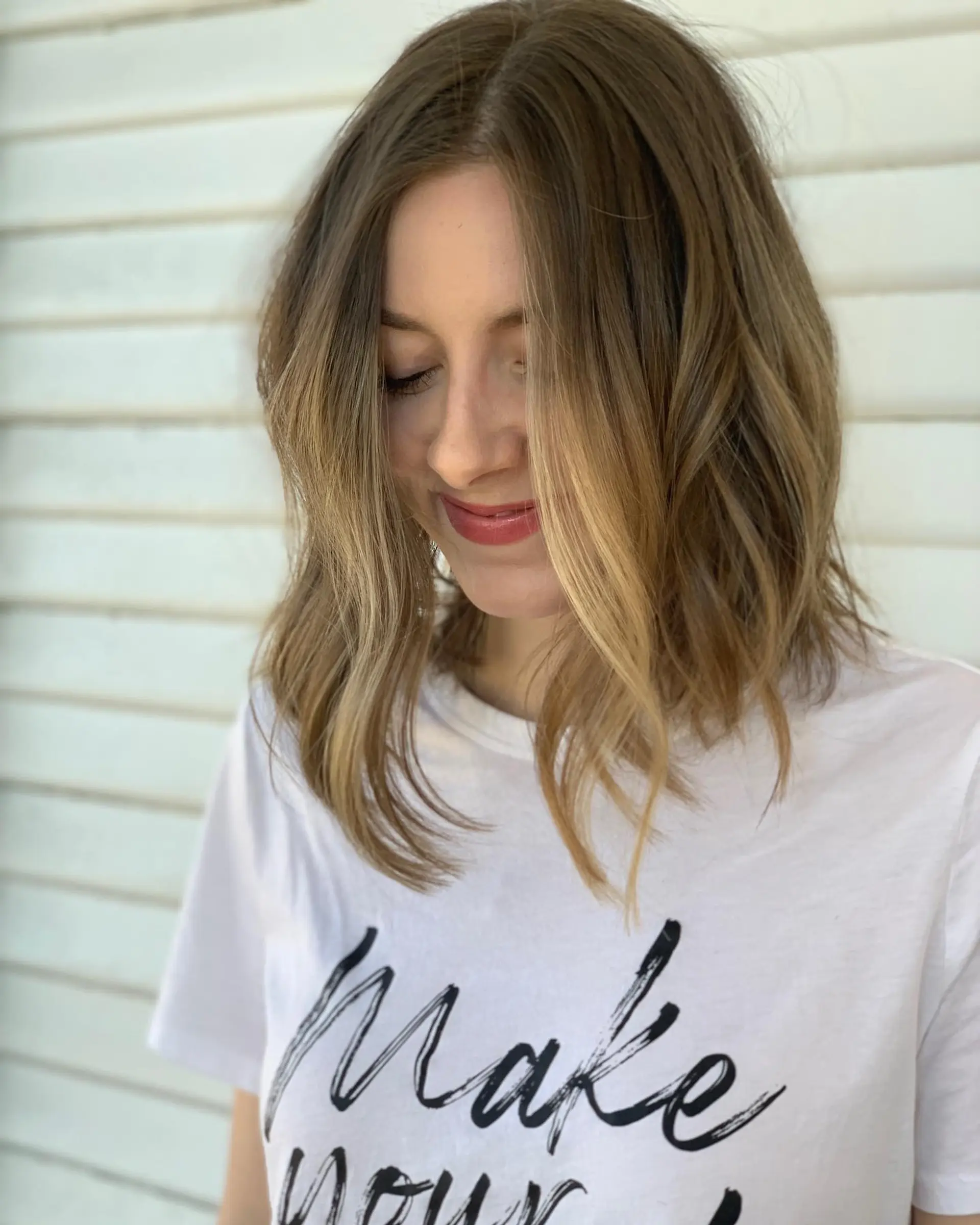 A textured collarbone-length lob styled with effortless, relaxed waves and soft honey blonde highlights. 1