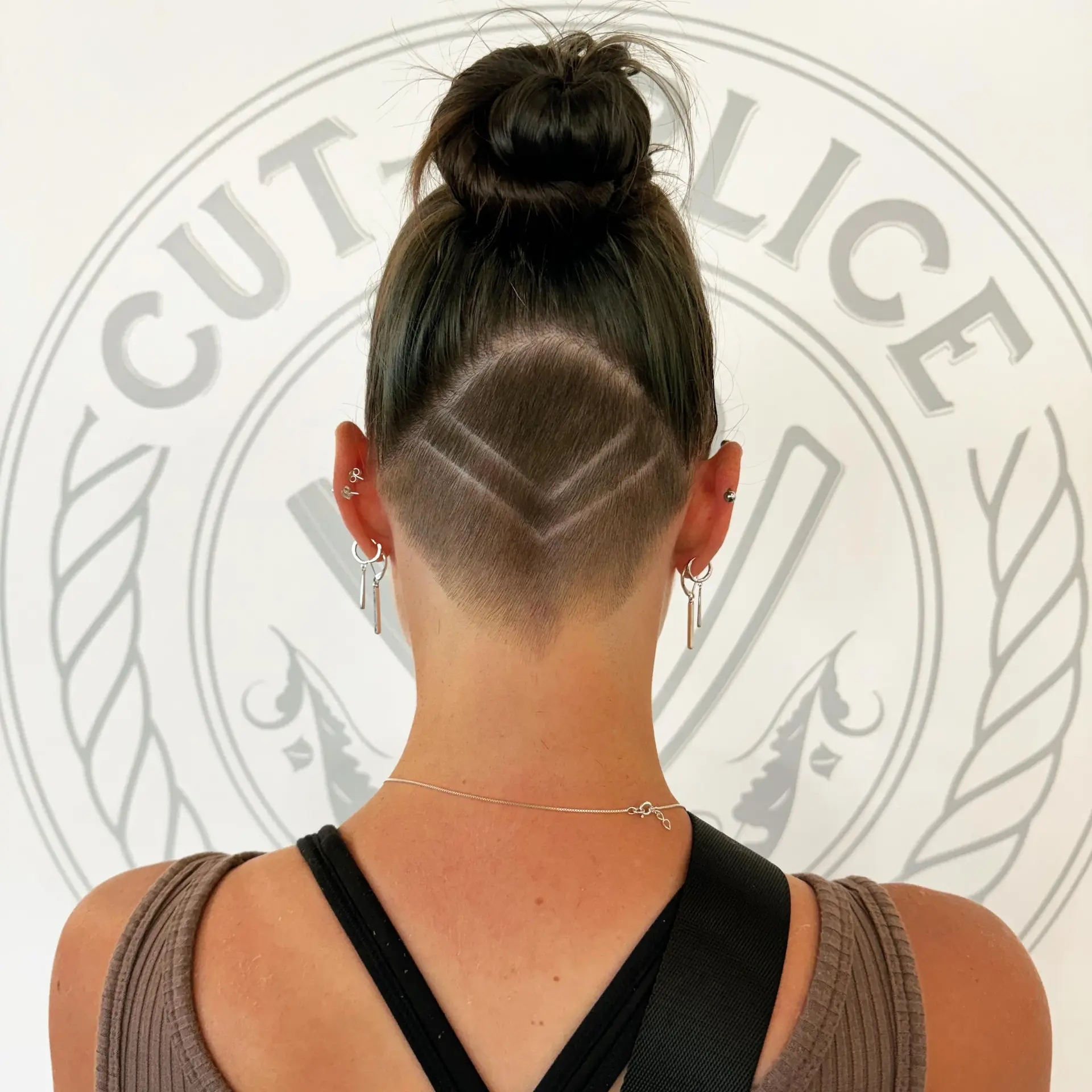 A shaved nape undercut featuring shaved geometric chevron lines beneath a high bun. 1