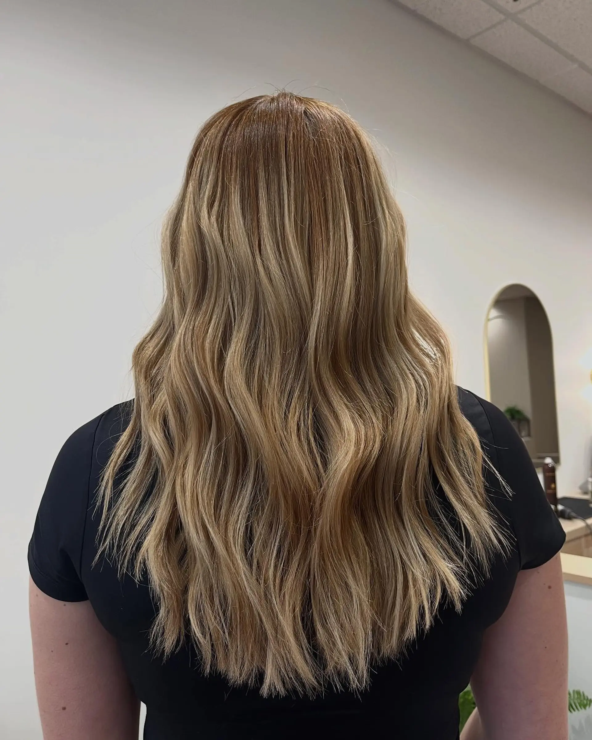 Long hair featuring a seamless golden blonde balayage styled in loose, textured waves. 1