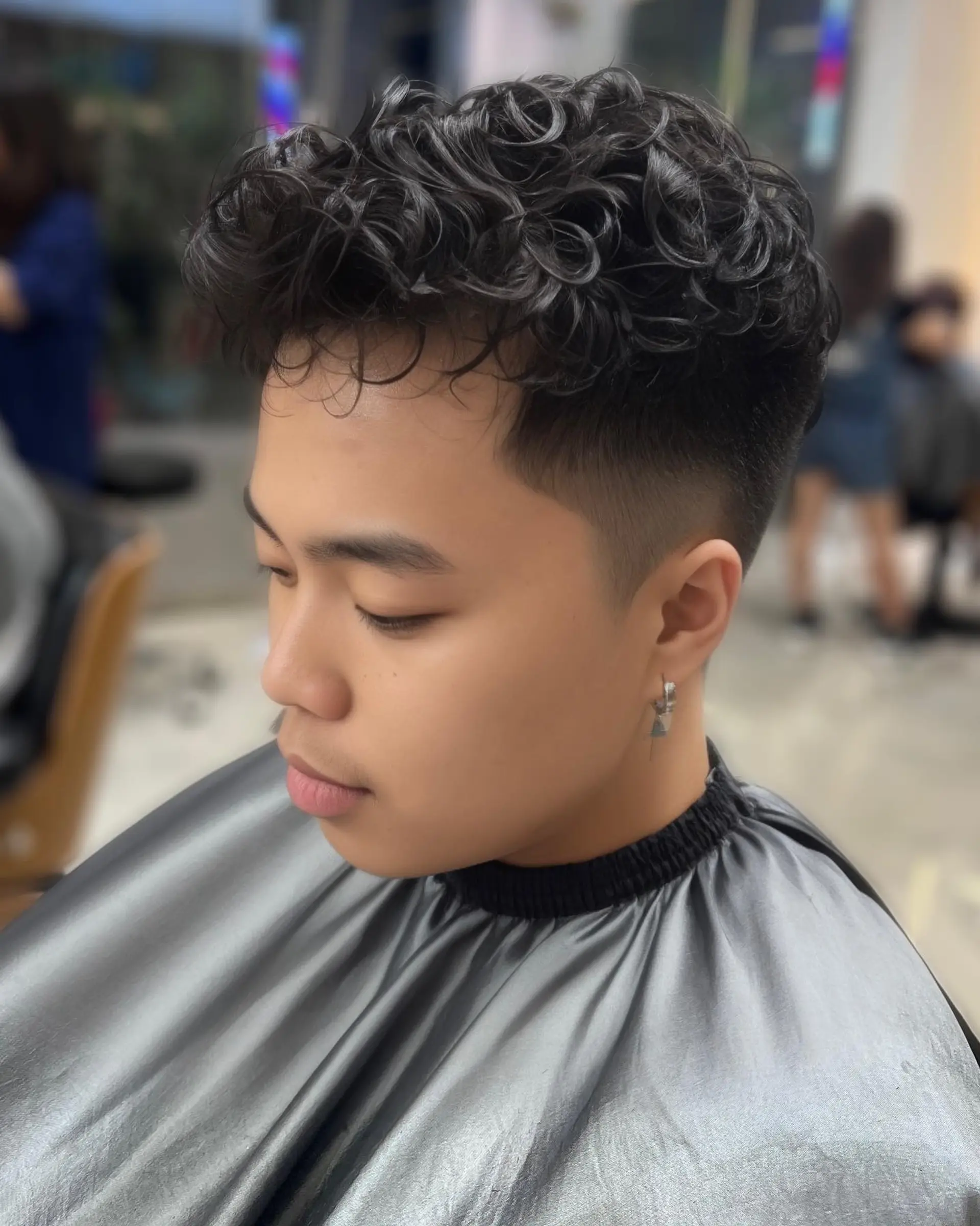 A modern curly hairstyle featuring a high fade and textured top. 1