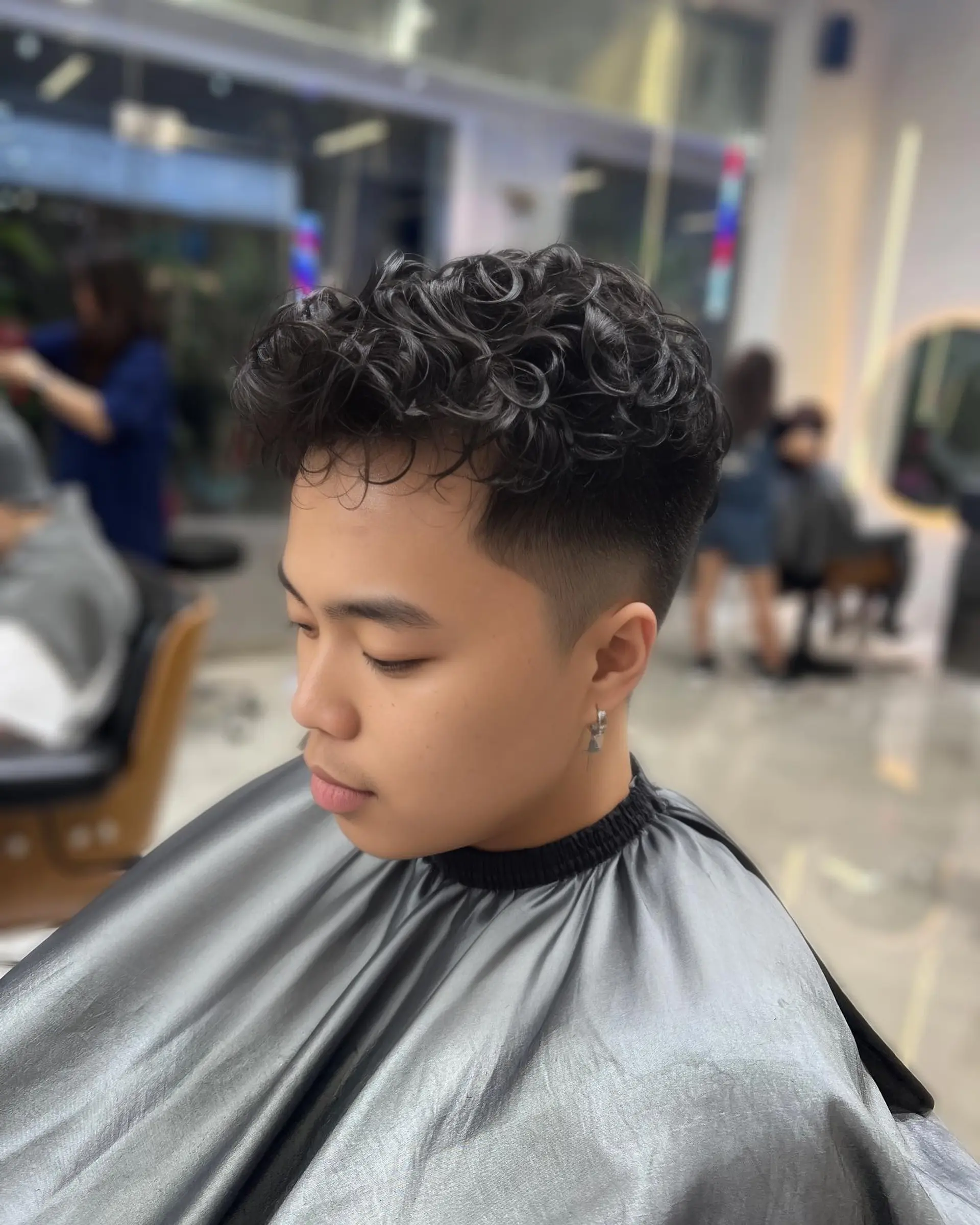 A modern curly hairstyle featuring a high fade and textured top. 2