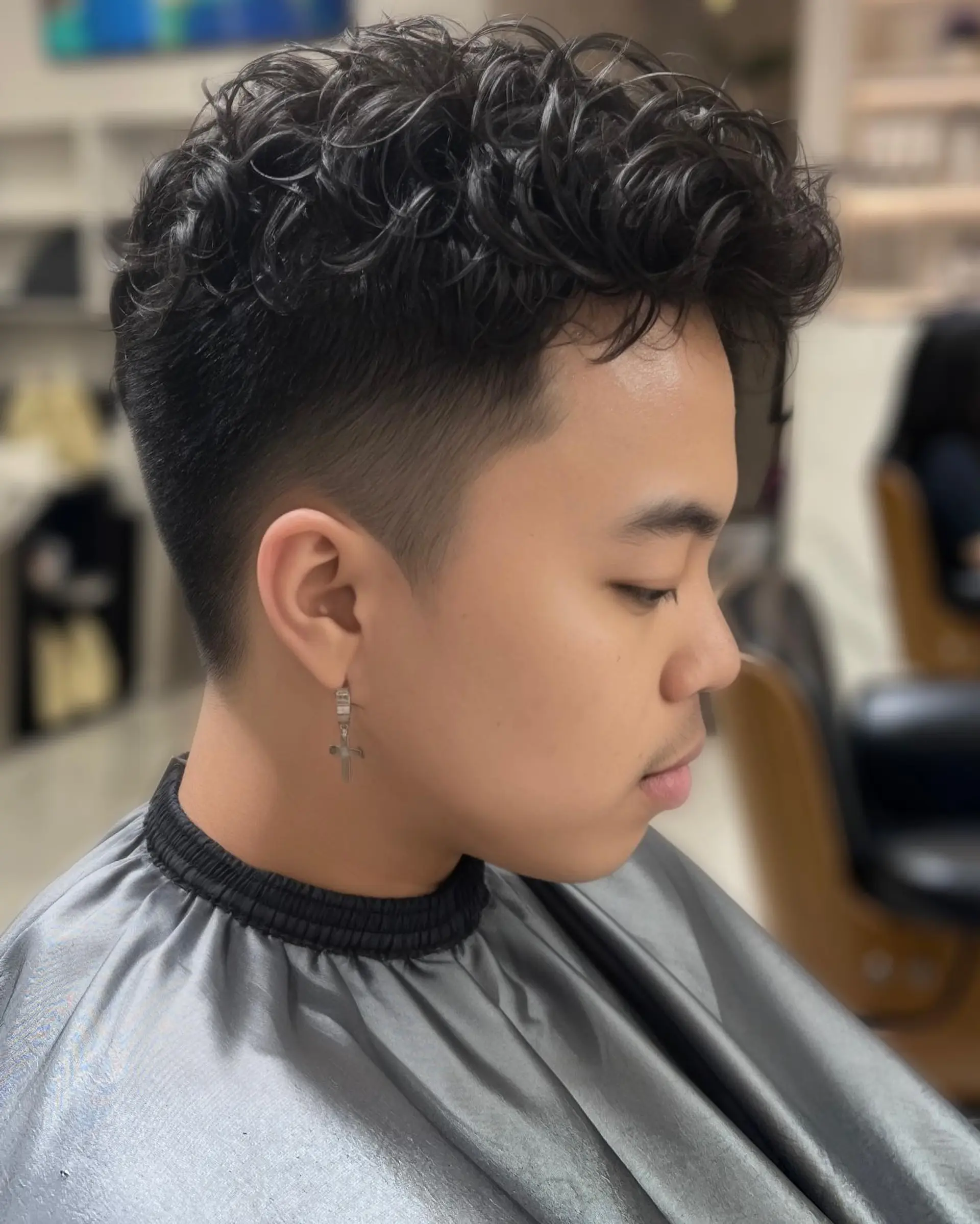 A modern curly hairstyle featuring a high fade and textured top. 3