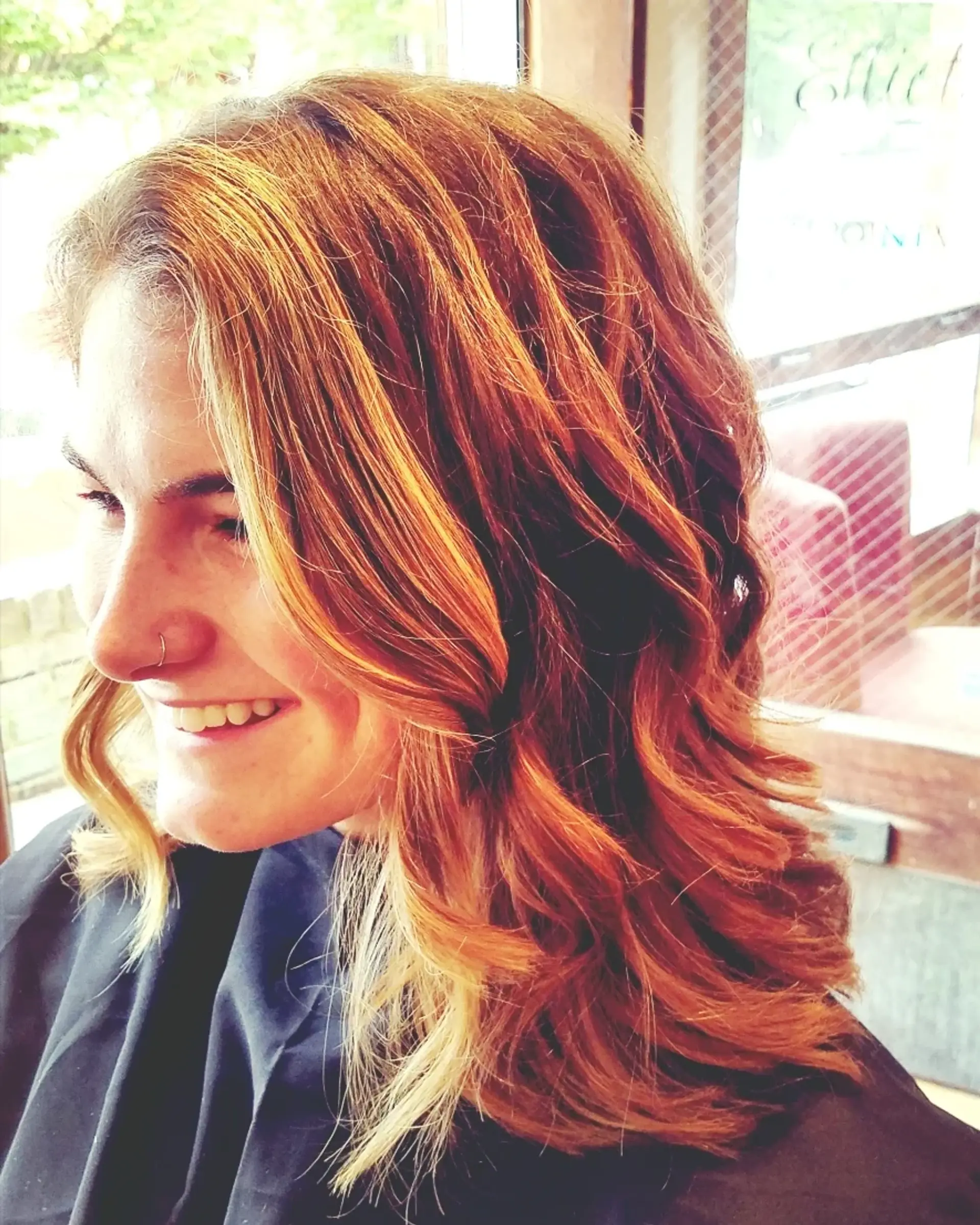 Medium-length layered cut styled in loose, bouncy waves with warm caramel and auburn balayage highlights. 1