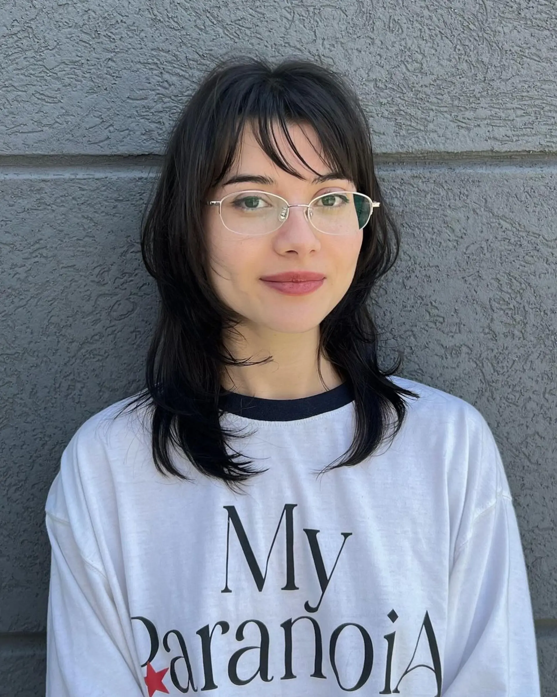 A Modern Layered Shag with medium-length, straight black hair, layers for volume, and a prominent face-framing fringe. 1