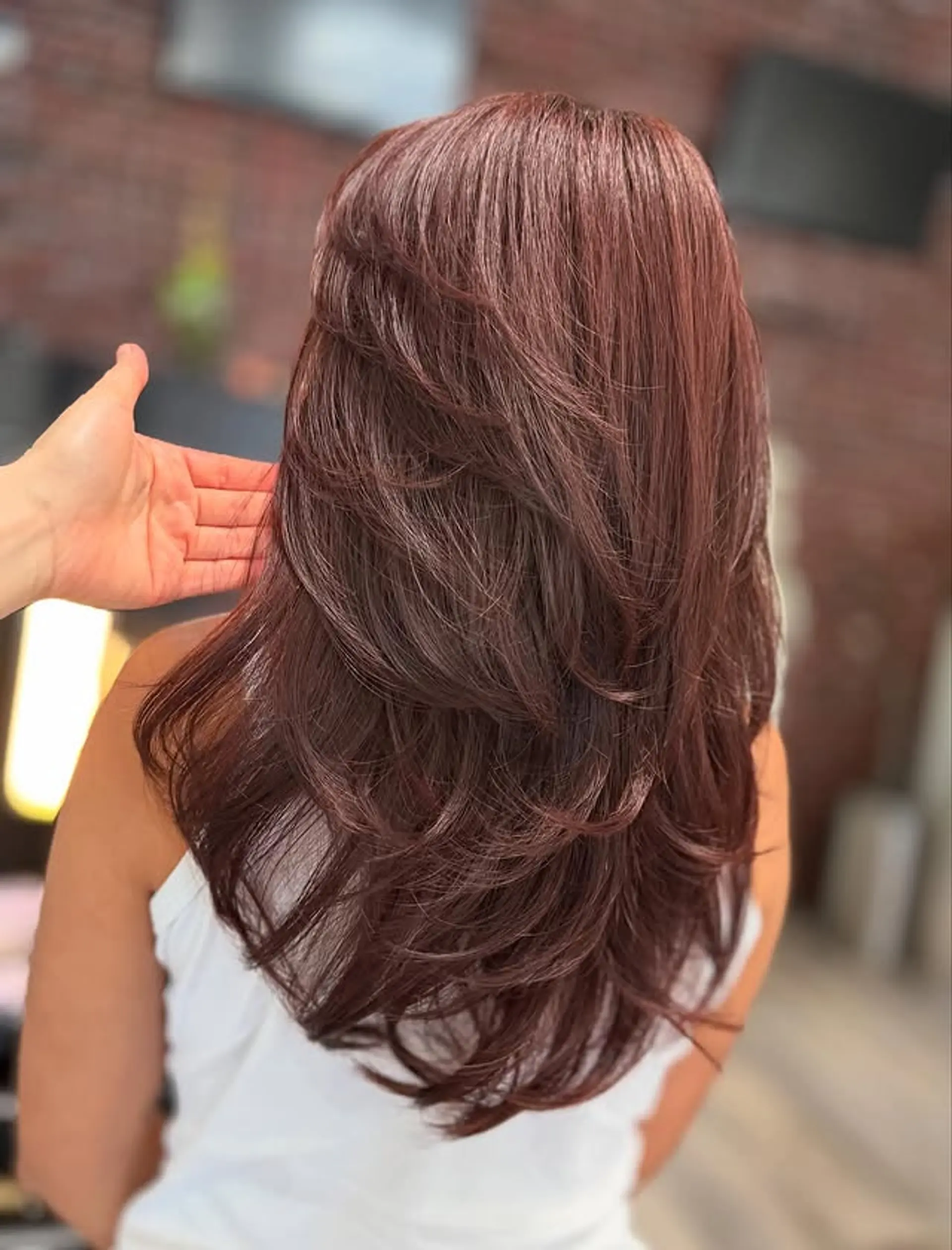 A stunning long layered haircut with impressive volume and flow. The layers are expertly cut to provide body and bounce, with the ends styled into soft, outward flips. 1