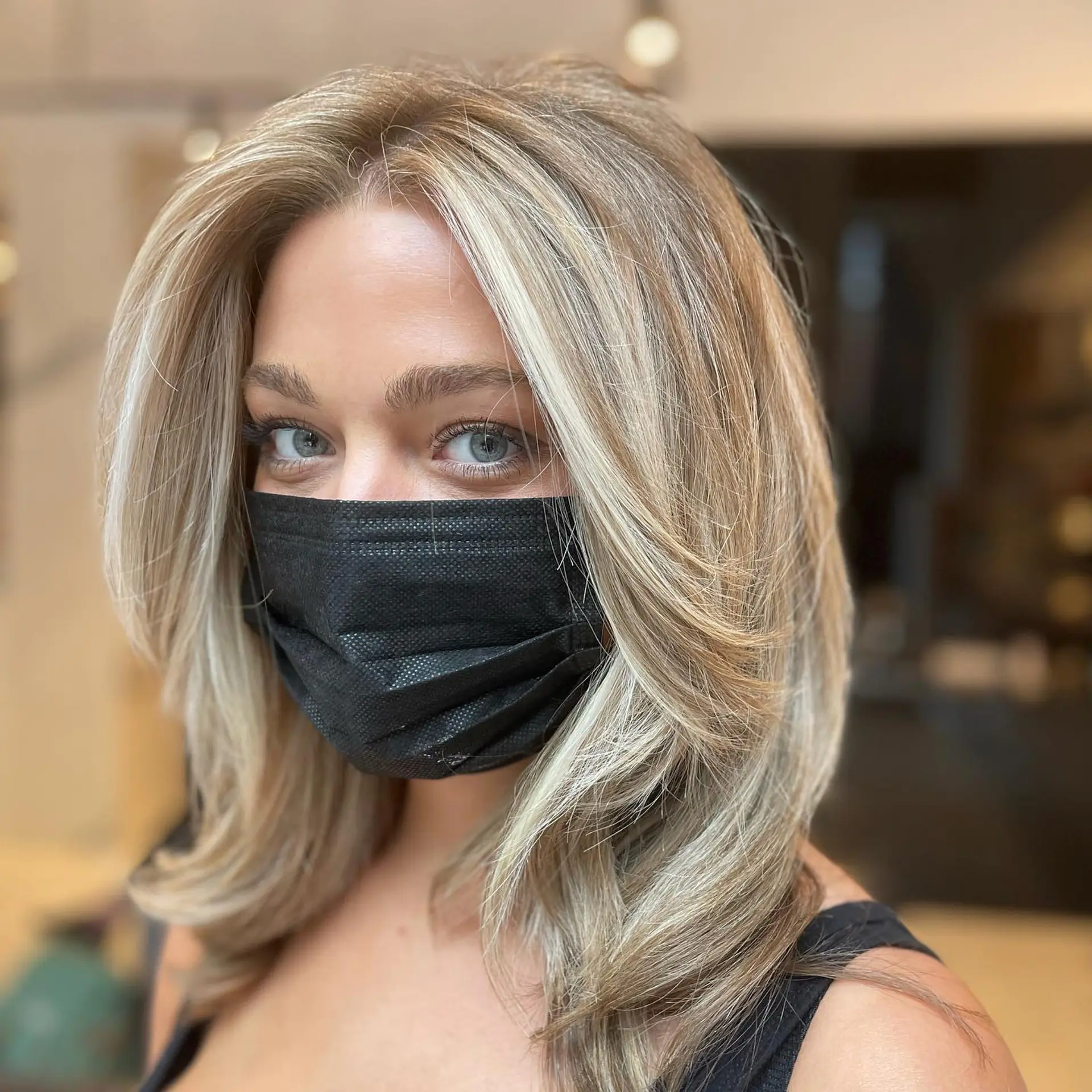 Medium-length dimensional blonde hair cut with face-framing layers and styled into a voluminous blowout. 1
