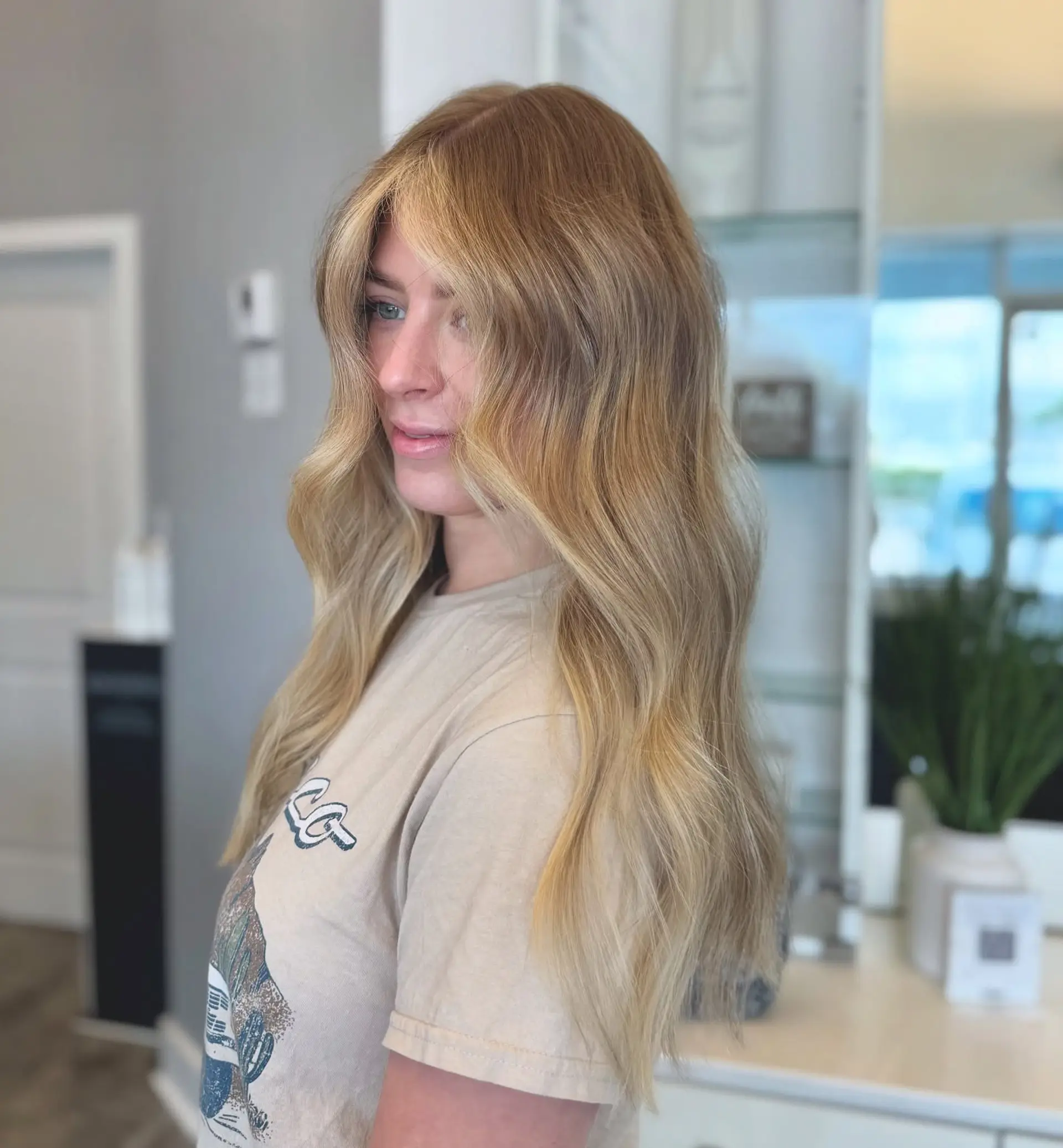 Long, golden blonde waves with flattering curtain bangs and subtle layering. 1