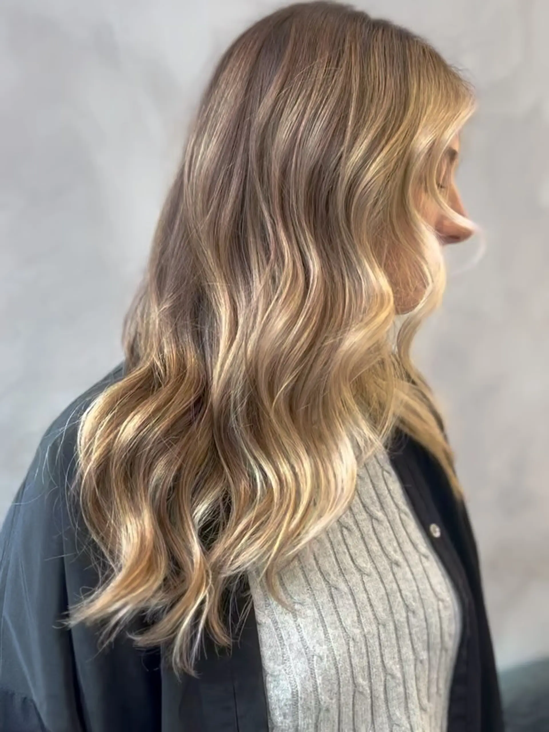 Long hair featuring dimensional golden blonde highlights styled into loose, flowing waves. 1