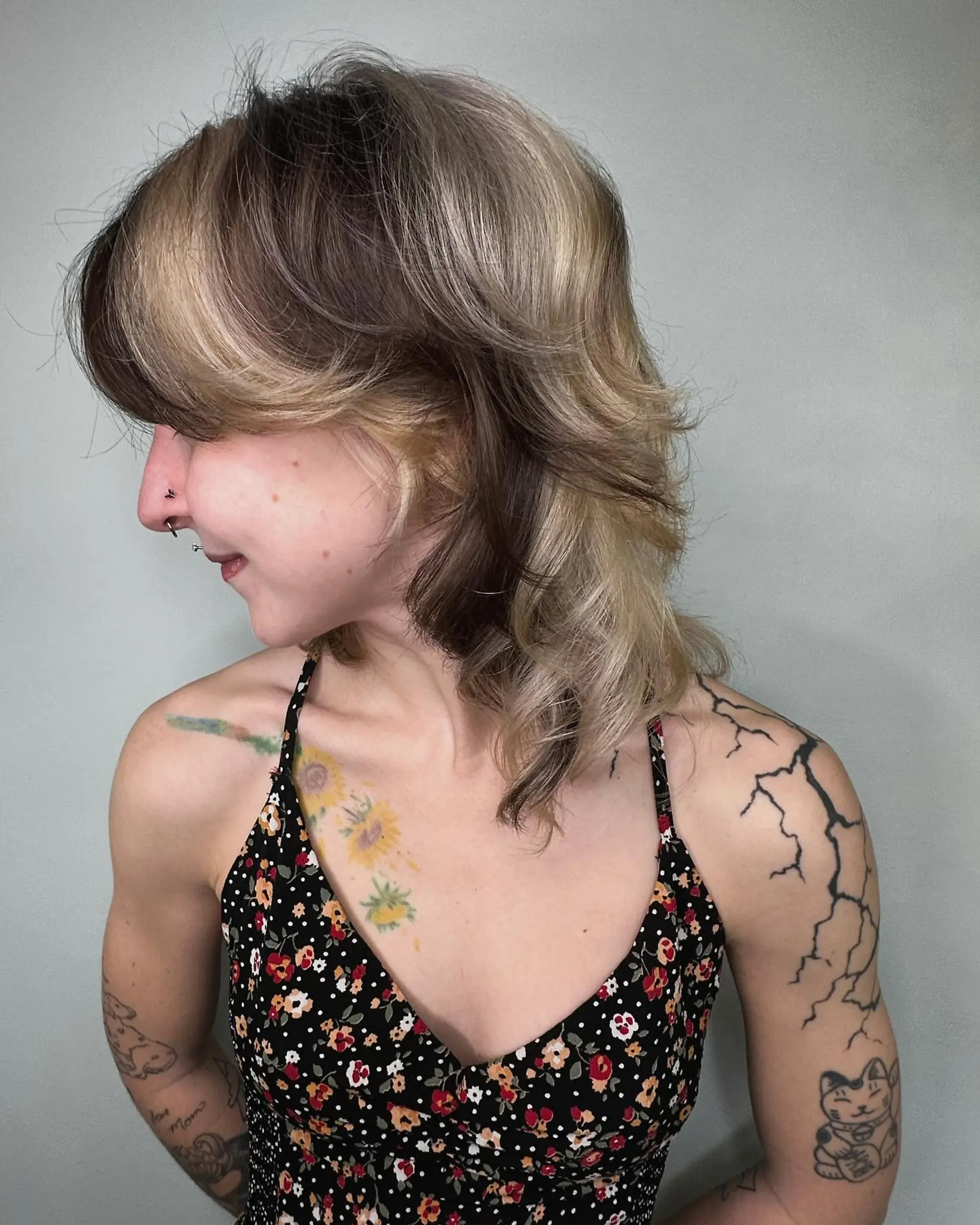 A medium-length textured shag haircut featuring contrasting panels of dimensional blonde and brunette with soft, flicked layers. 1