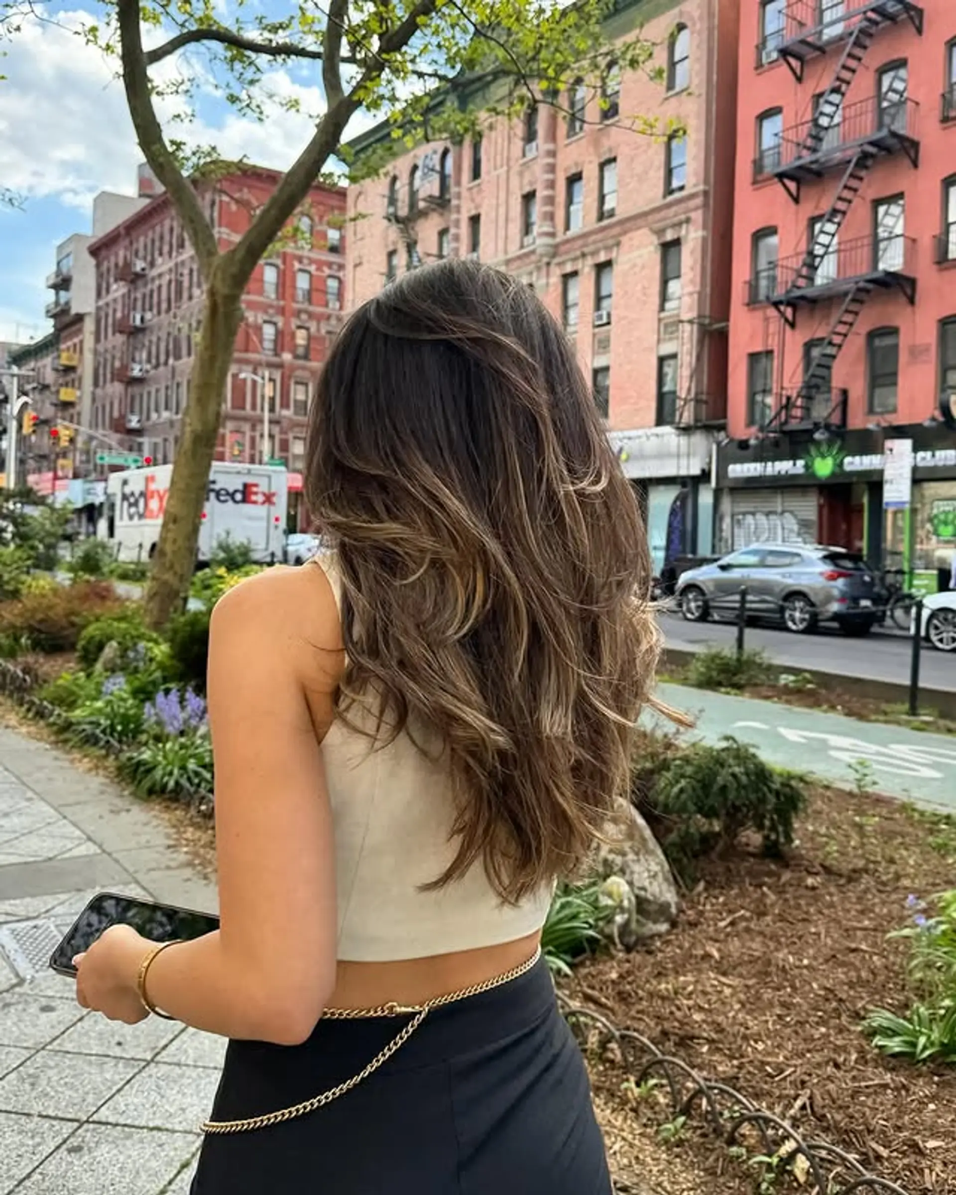 A long, wavy hairstyle with a bronde balayage and layered cut. 1