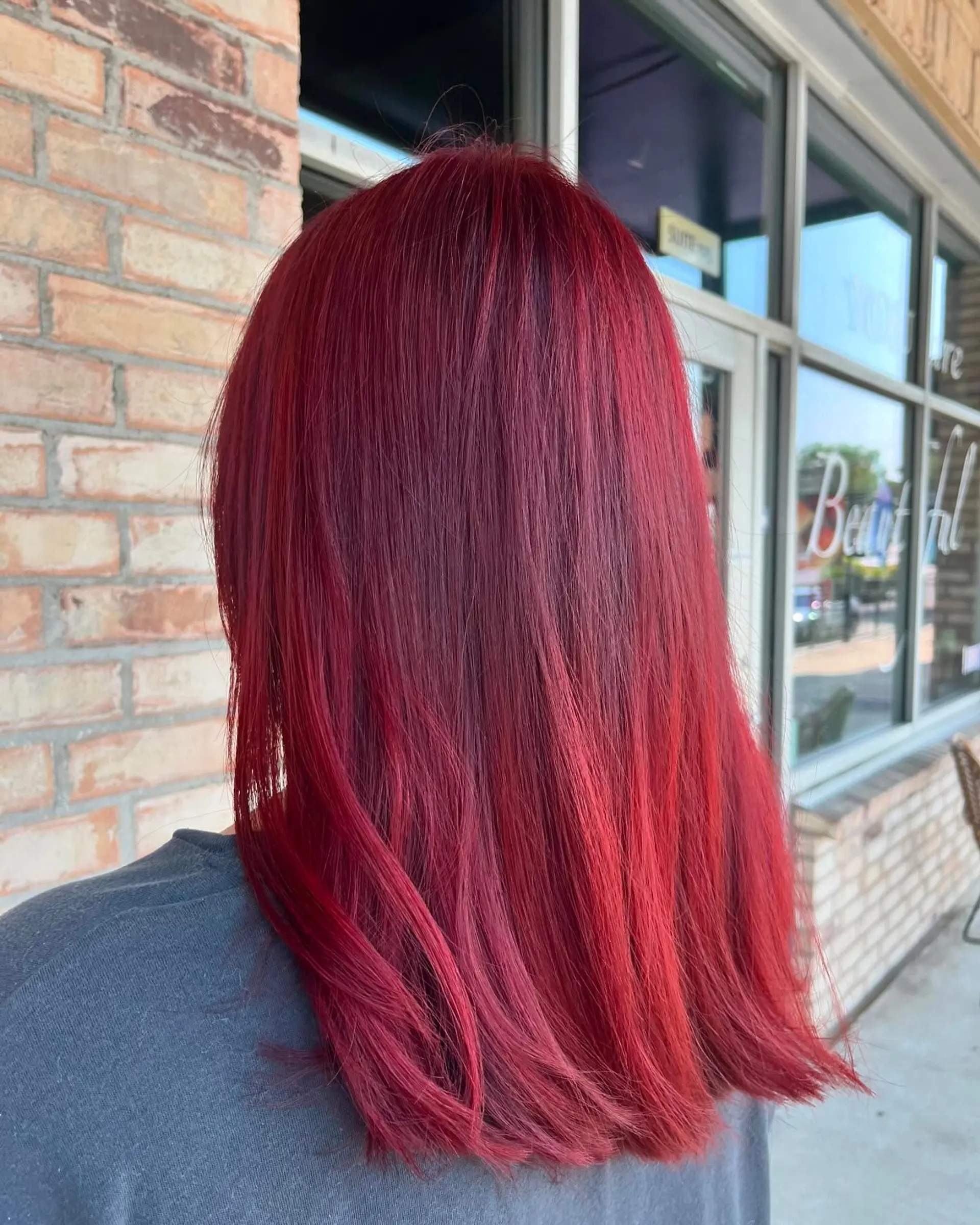 Rich, vibrant crimson red color on medium-length hair styled smooth and straight. 1