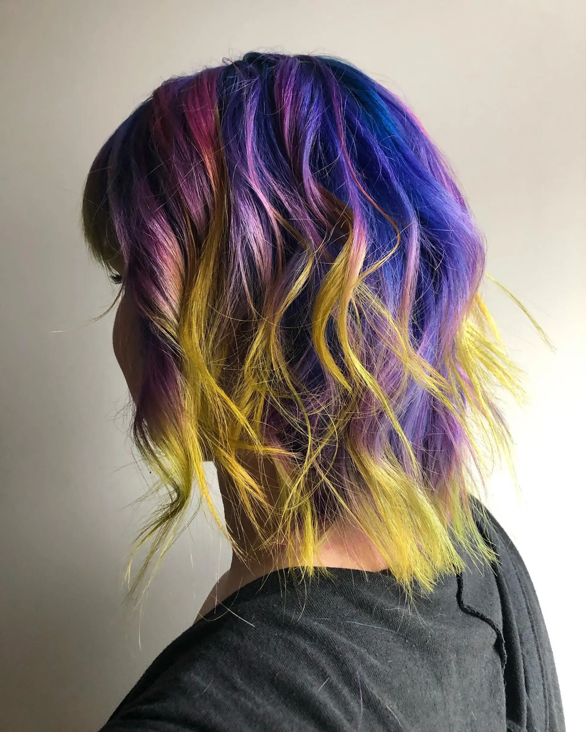 A wavy lob haircut with a vibrant rainbow of colors achieved through balayage. 1