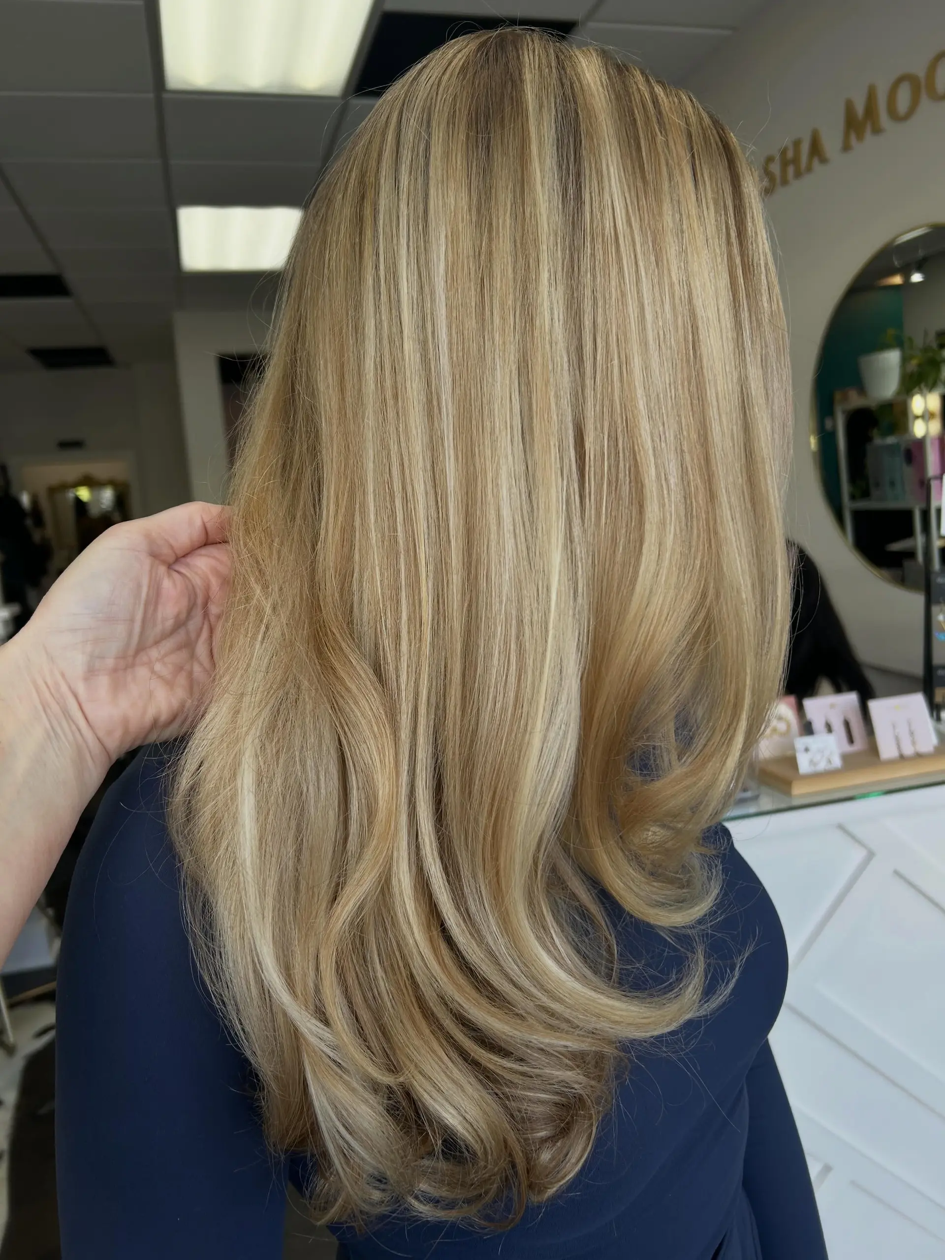 Long warm blonde hair with blended highlights styled into a sleek blowout with soft, turned-under curled ends. 1