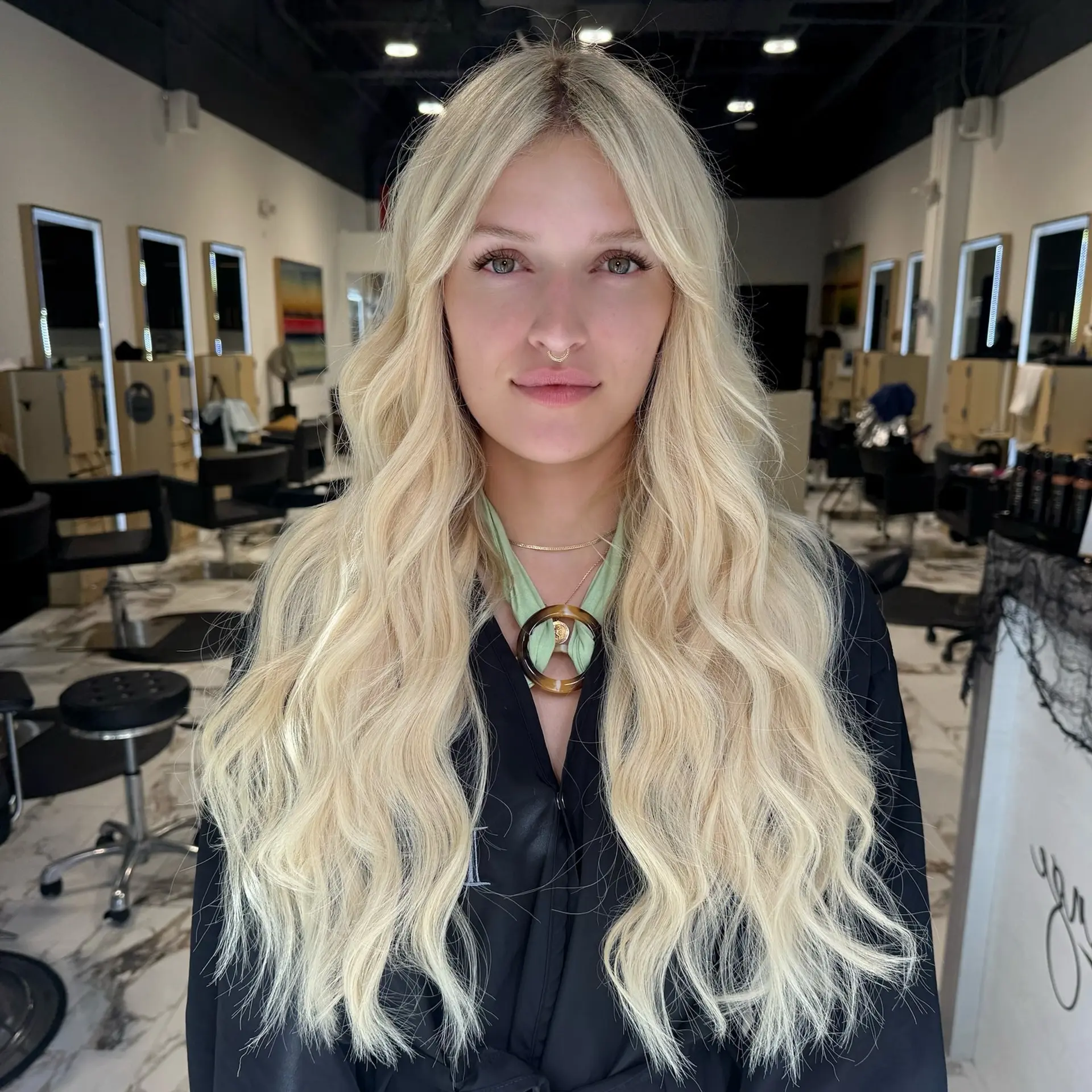 Extra-long platinum blonde hair enhanced with volume-boosting weft extensions and styled in soft beach waves. 1