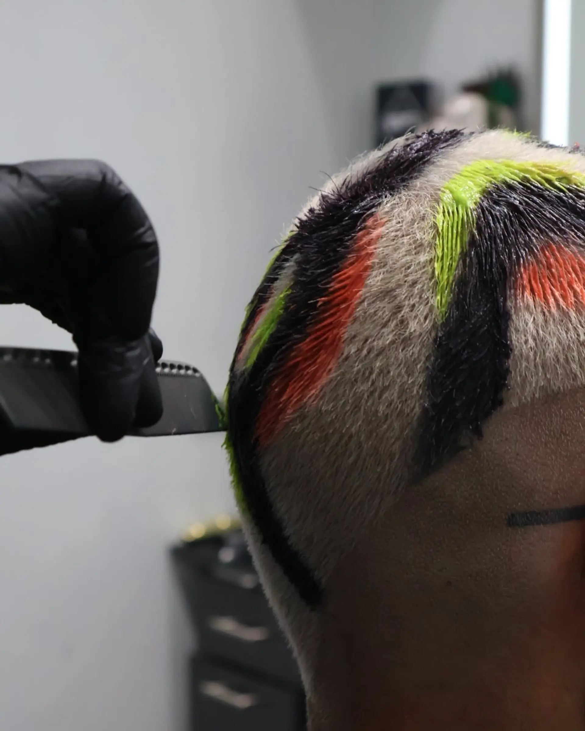 A buzzcut with color block sections of black, orange, and green. 1