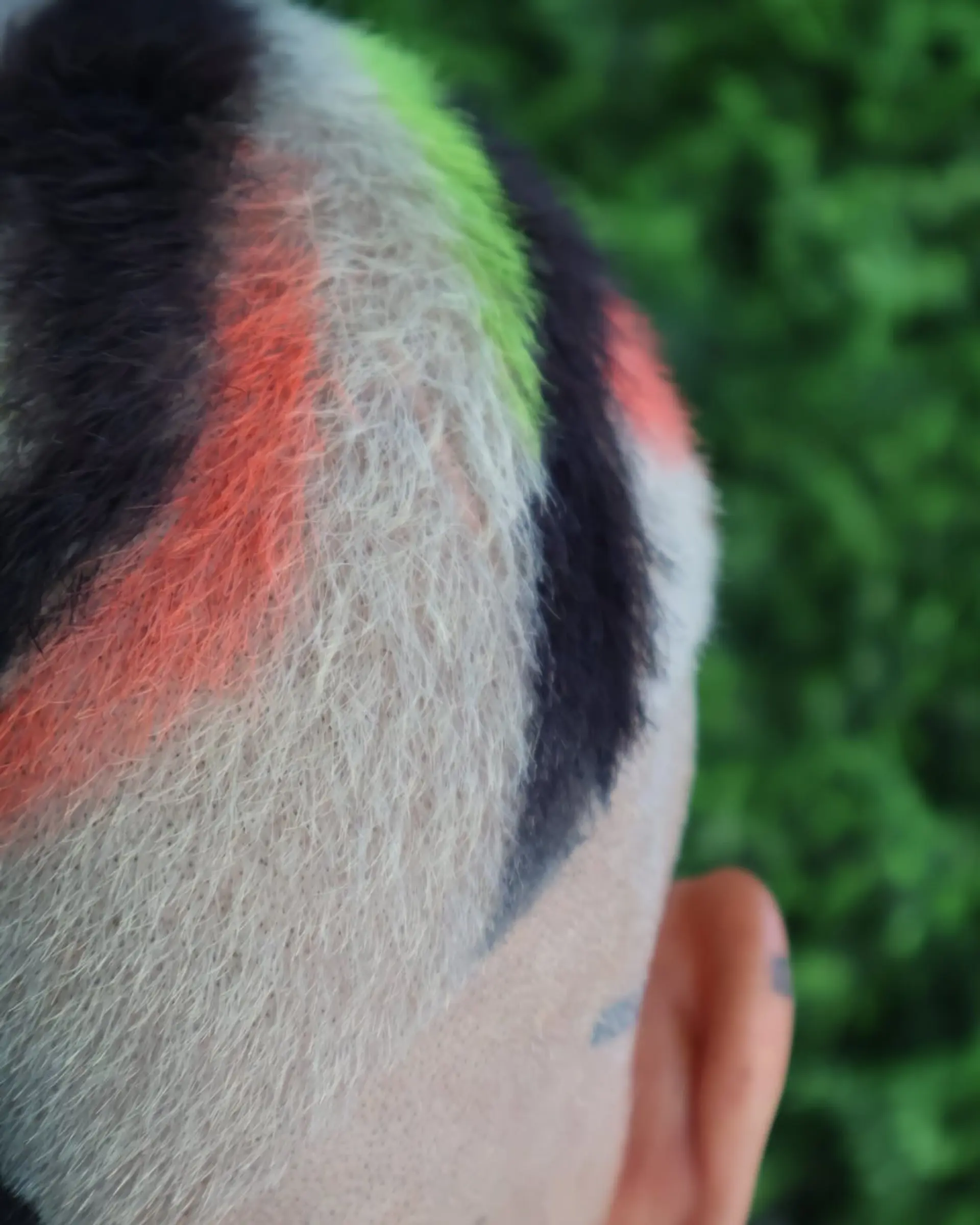 A buzzcut with color block sections of black, orange, and green. 4