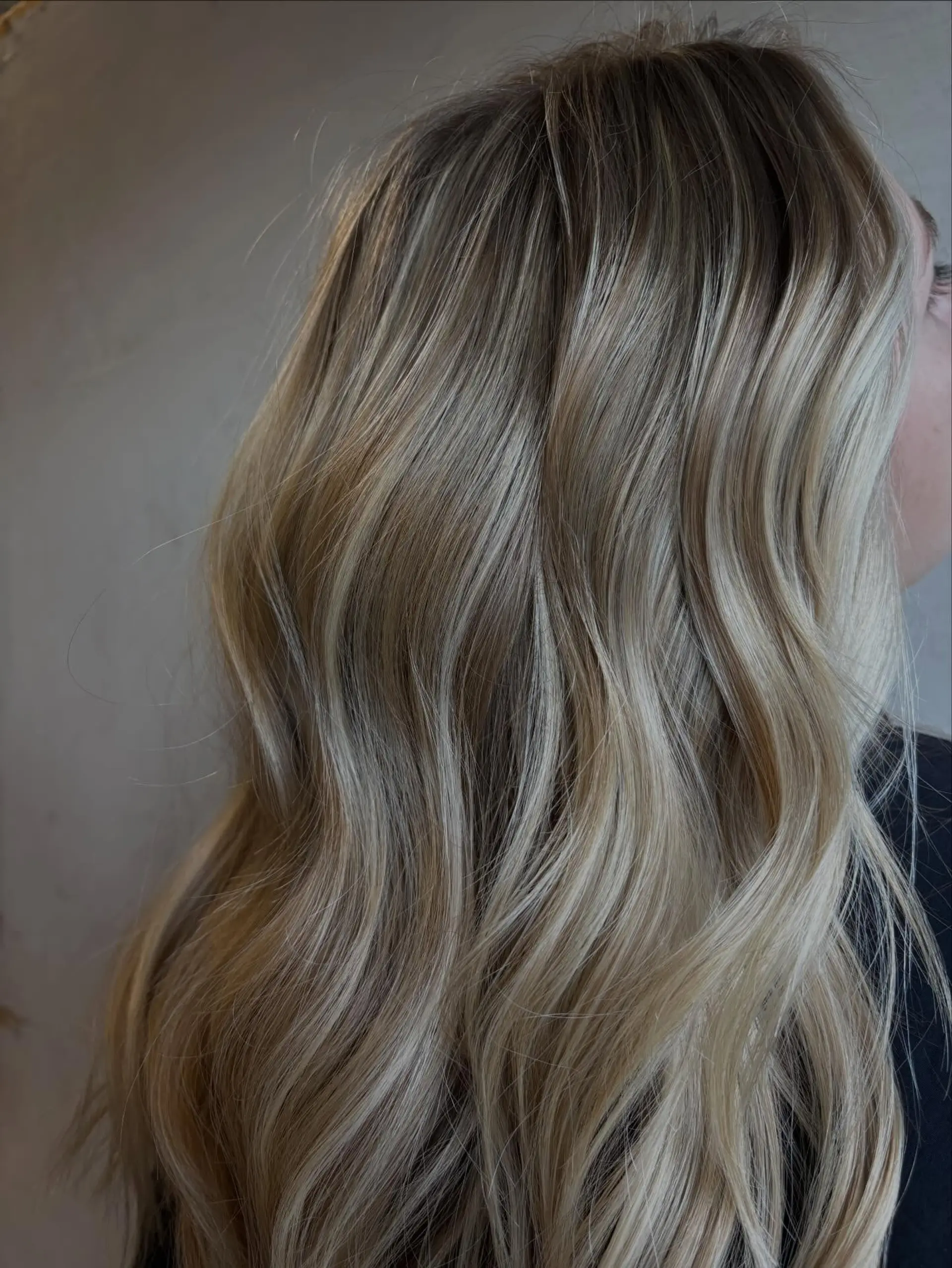Lived-in dimensional blonde styled into soft, flowing textured waves with a natural root shadow. 1