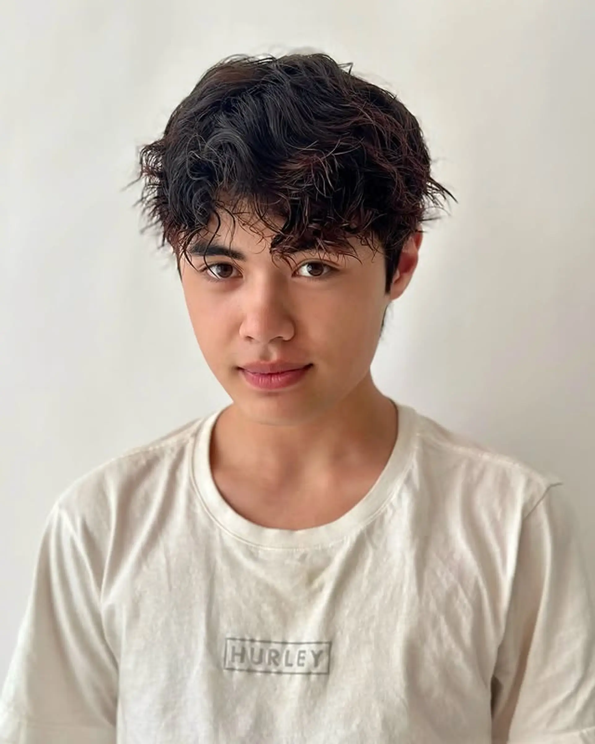 A short, textured curly style with a messy fringe. 1