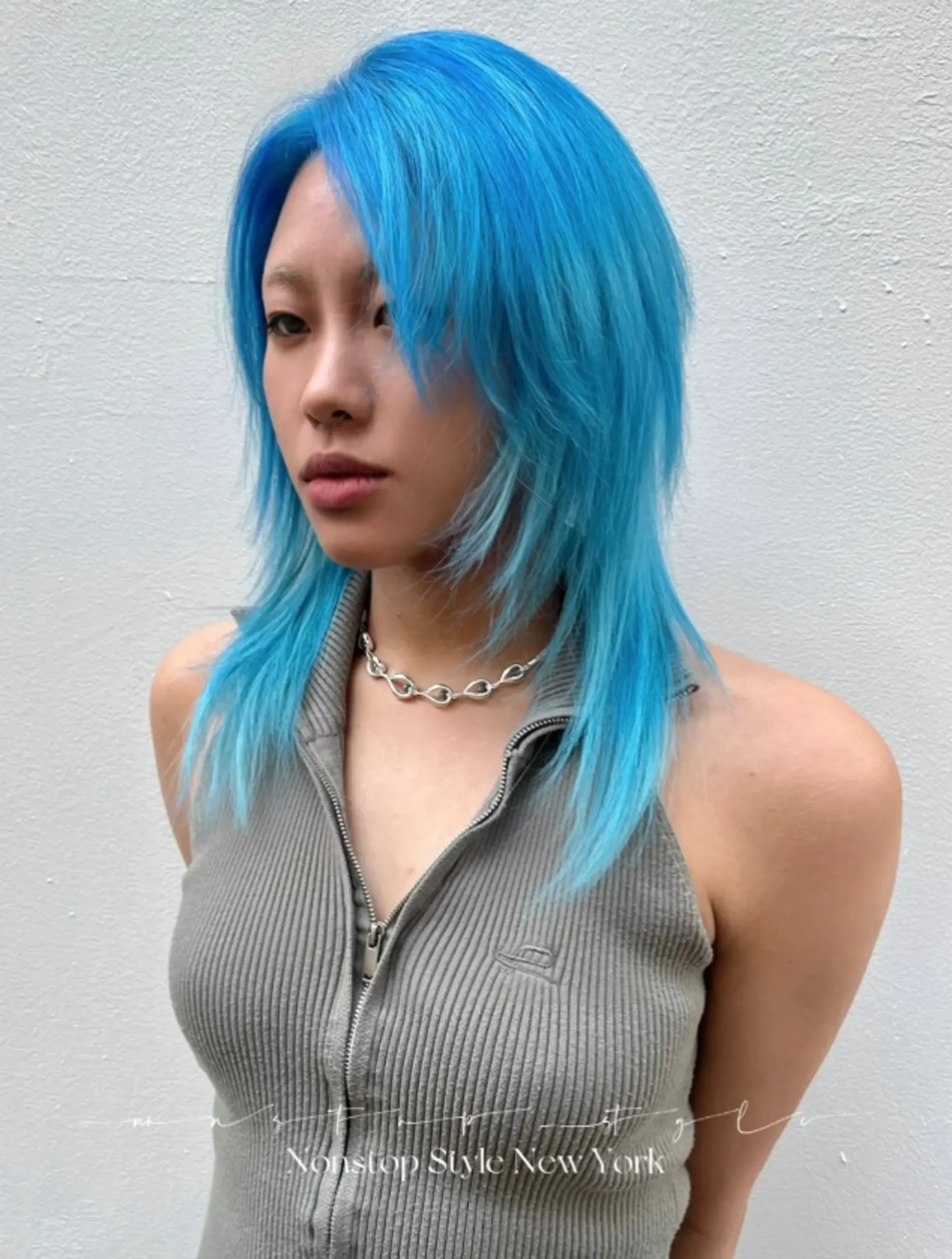 The vibrant electric blue hairstyle features straight, medium-length hair styled into a shag cut with multiple layers. The layers frame the face and add volume, with feathered ends and a slight side part for a stylish, edgy look.
(NonstopStyle: by Neil) 1