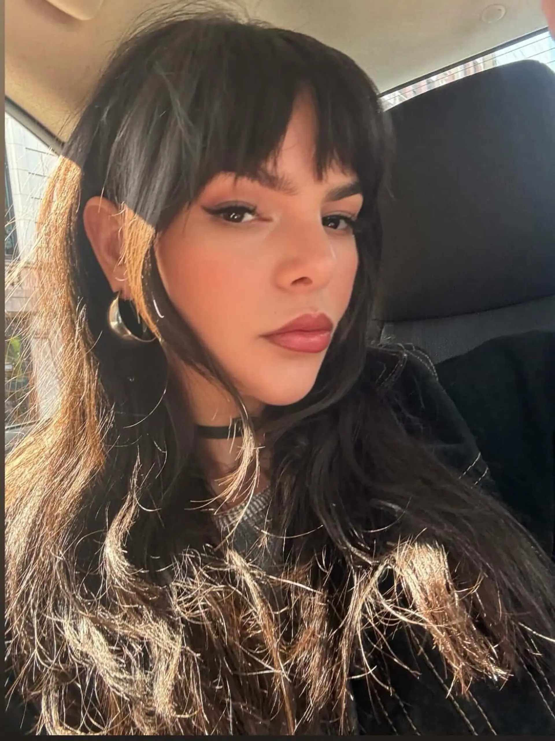 Long textured dark hair featuring full straight-across bangs and soft face-framing layers. 1