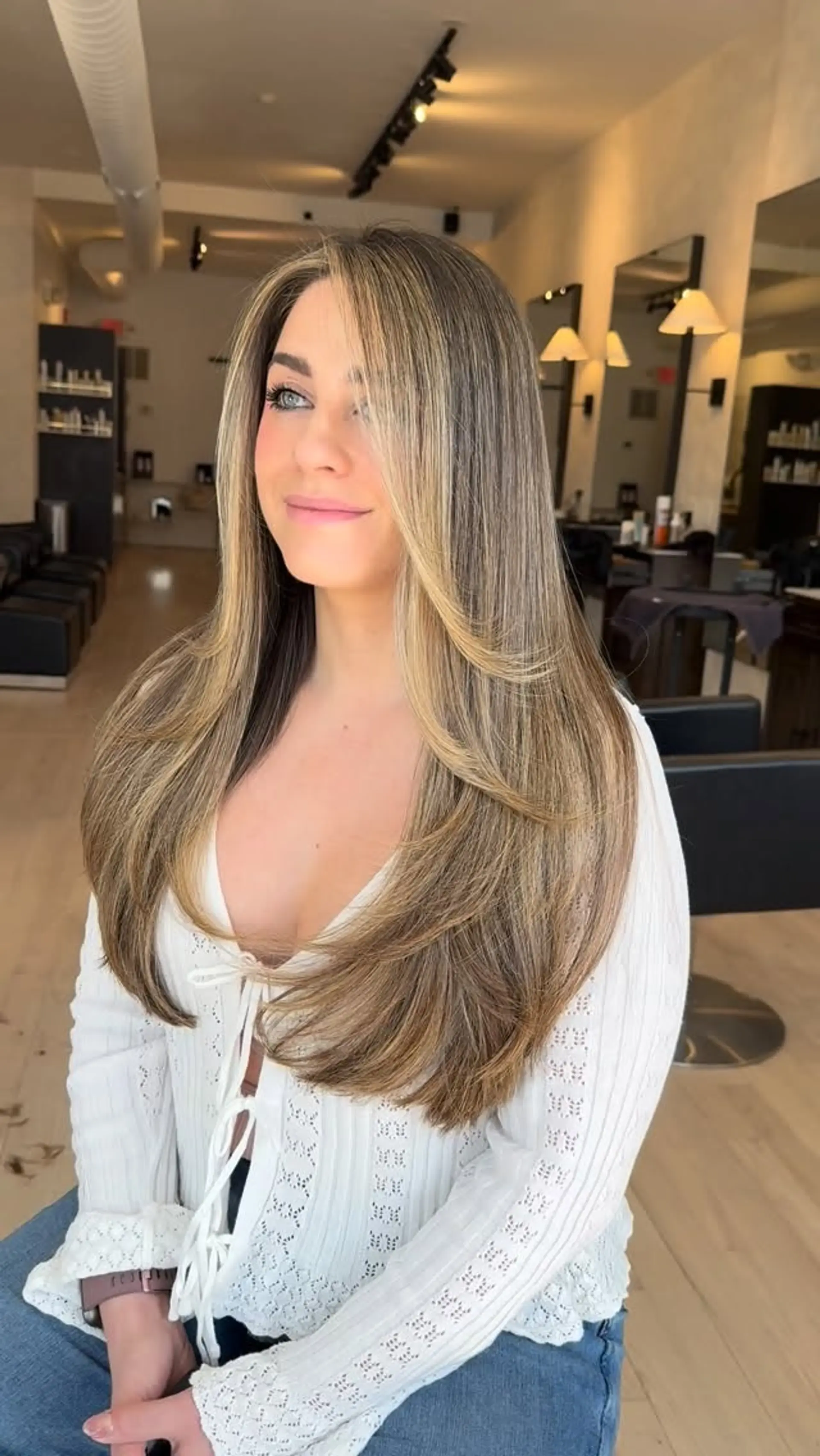 Long, flowing dimensional bronde hair featuring soft face-framing layers and smooth, inward-curling ends from a round-brush blowout. 1