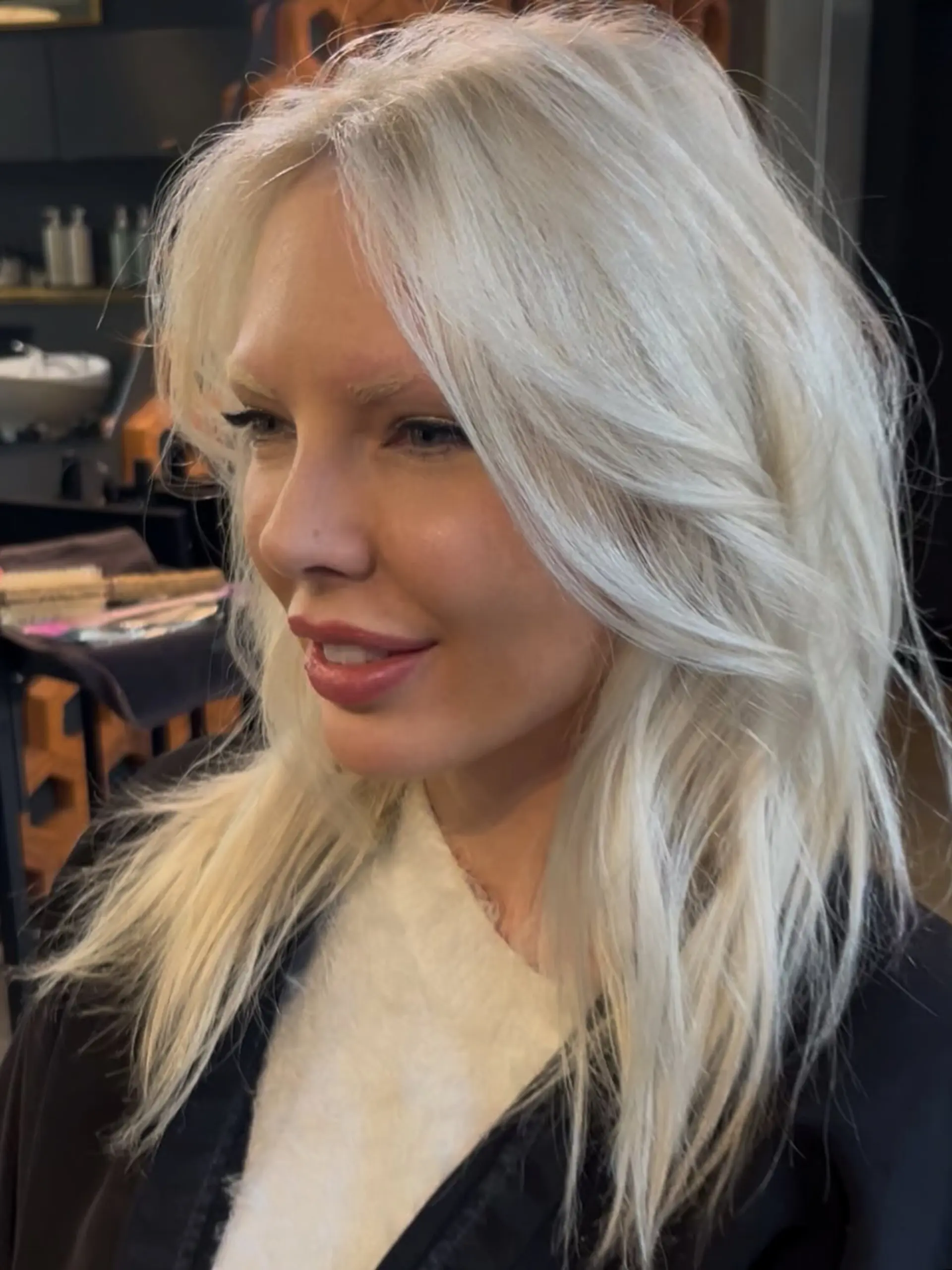 Long icy platinum blonde hair styled with soft, face-framing feathered layers and textured volume. 1