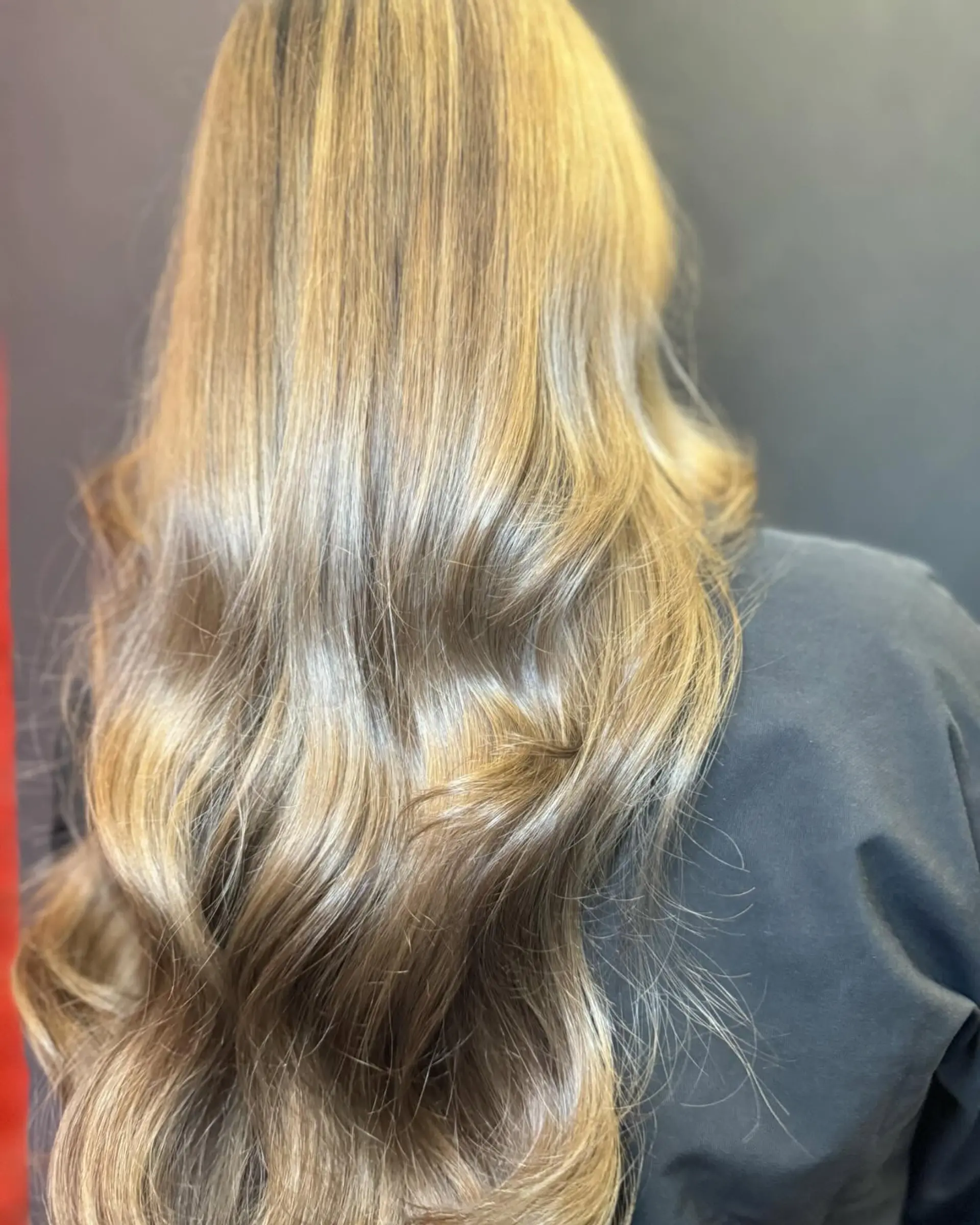 Long cascading hair featuring a soft mushroom brown to beige blonde balayage, styled in smooth, lustrous waves. 1