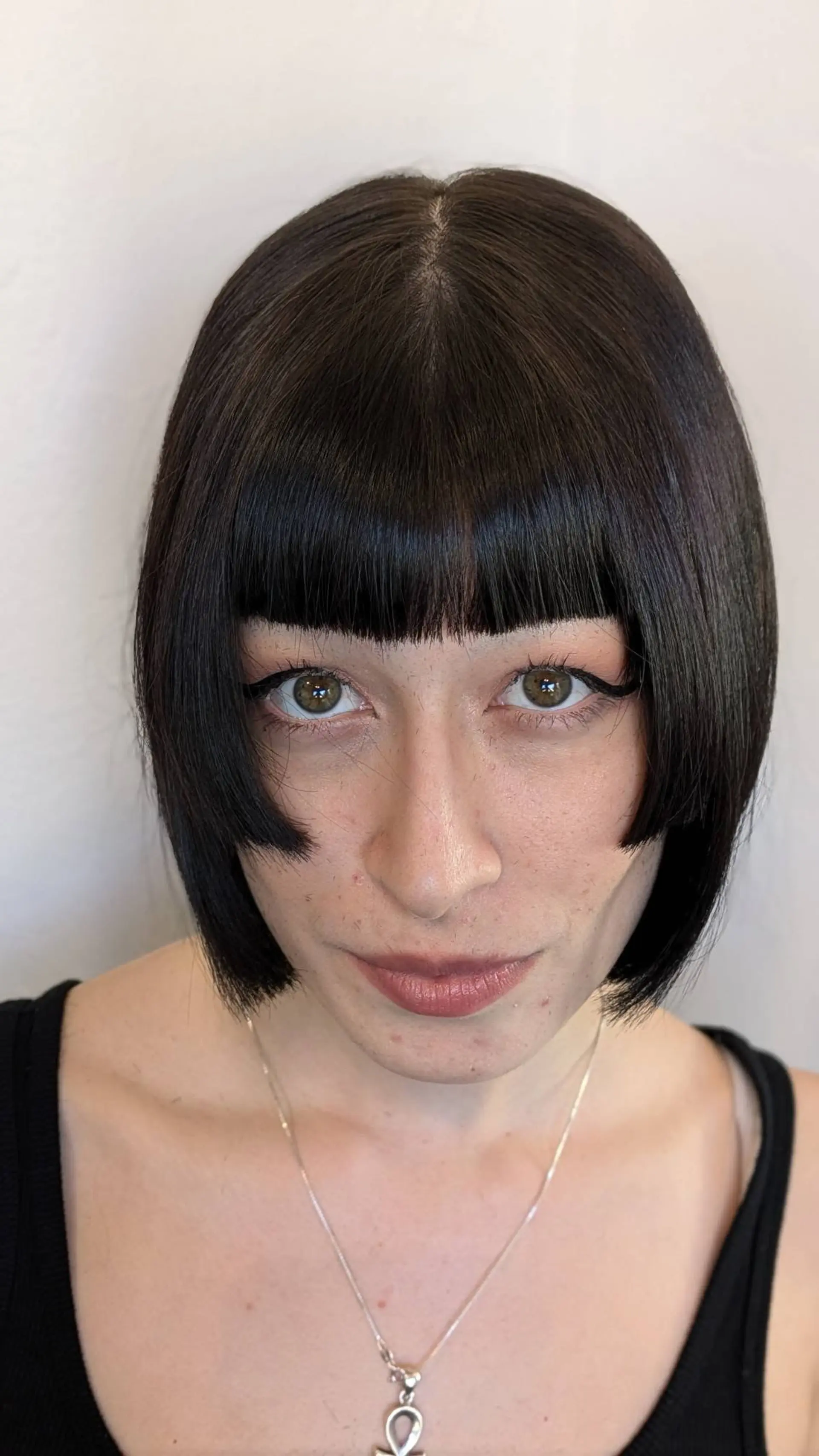 A sleek dark chin-length bob featuring straight blunt bangs and sharp cheekbone-length disconnect steps framing the face. 1