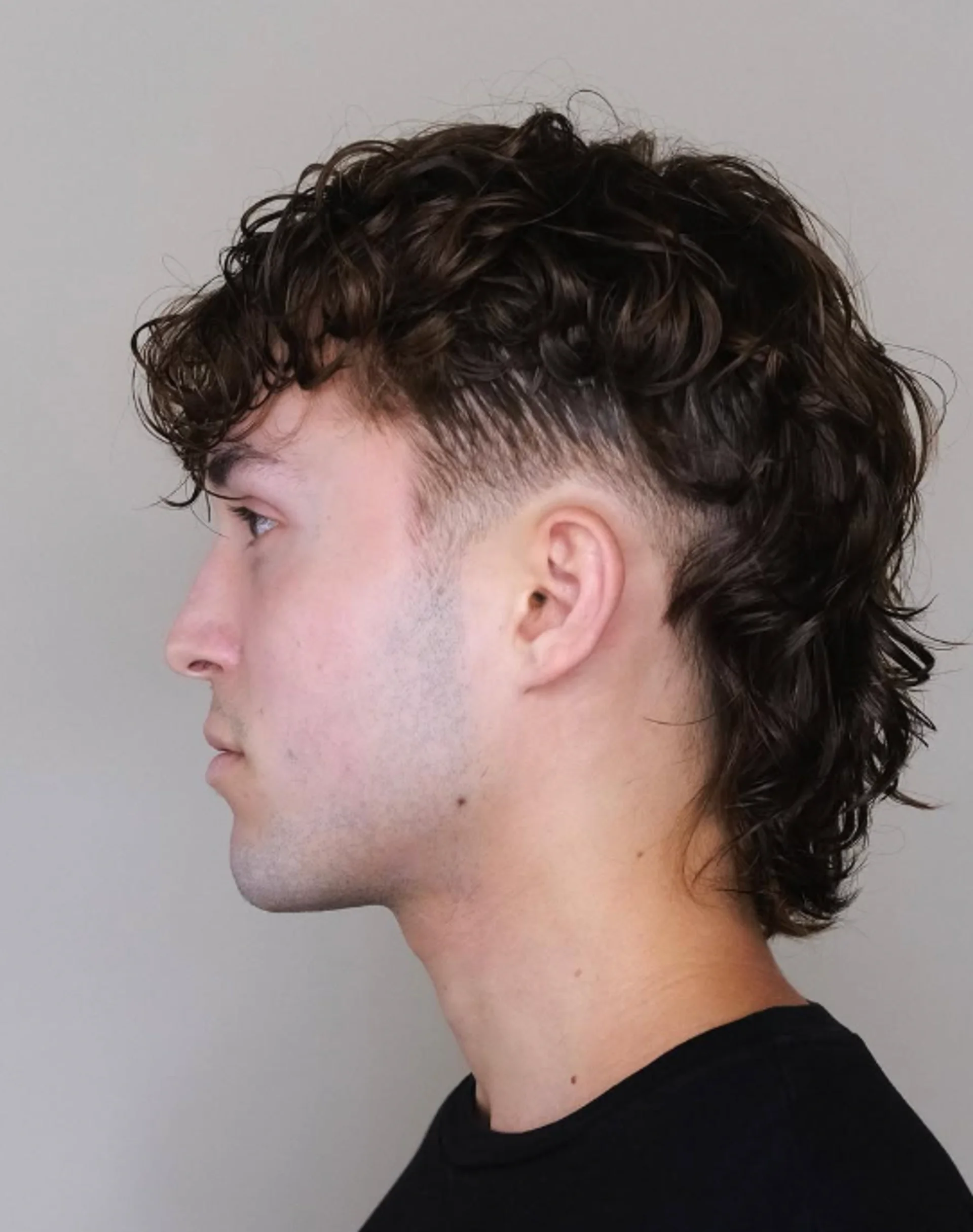 Man with a textured curly taper fade, a top men's curly hair trend for 2025 in NYC, showcasing sharp lines and natural texture. - Preview 2