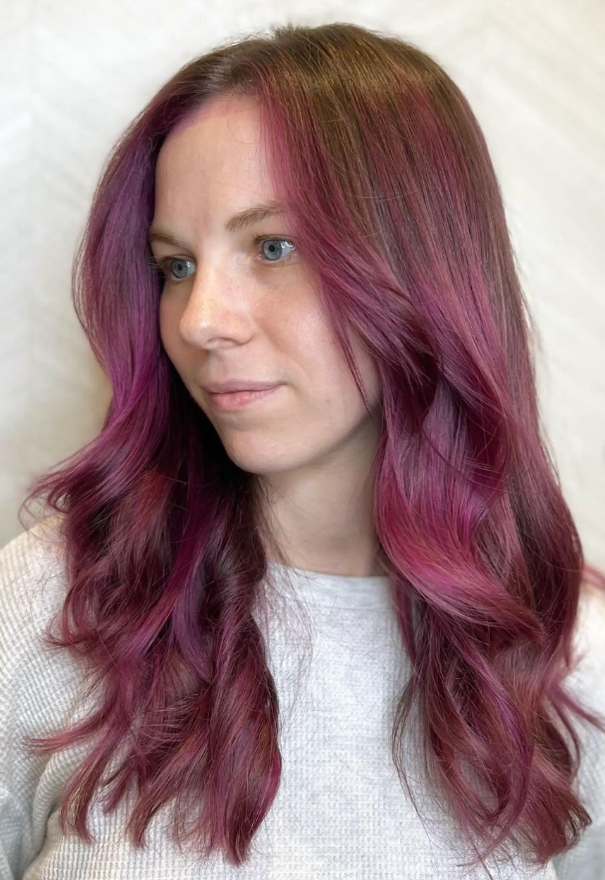 Long, wavy locks with a vibrant gradient of pink and purple colors, featuring soft waves that frame the face and a shiny finish. 1