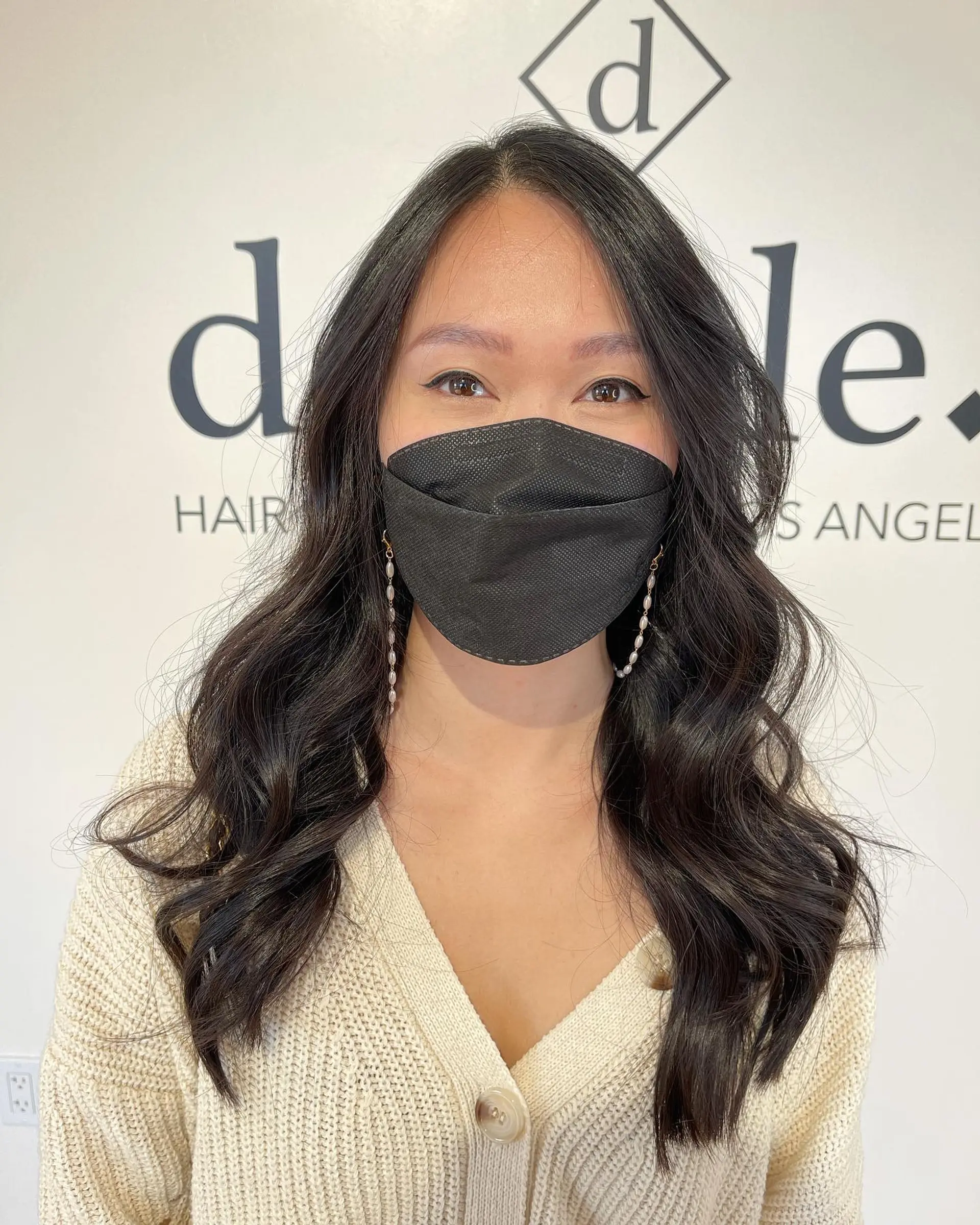 Long dark brown hair styled with soft, voluminous waves and face-framing curtain bangs. 1