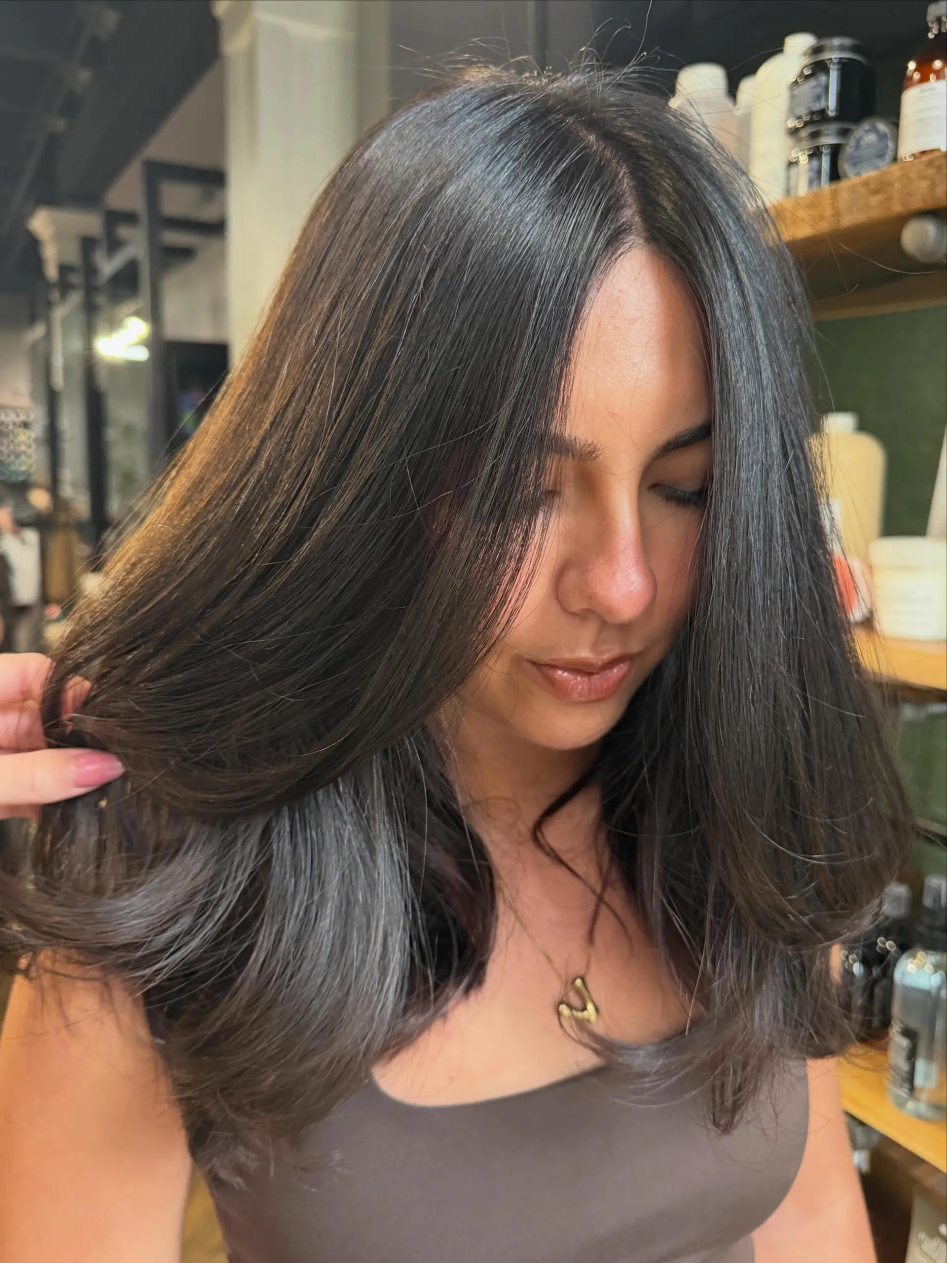 Medium-length dark brown hair cut with soft, face-framing layers and styled into a voluminous, bouncy blowout with curled-under ends. 1