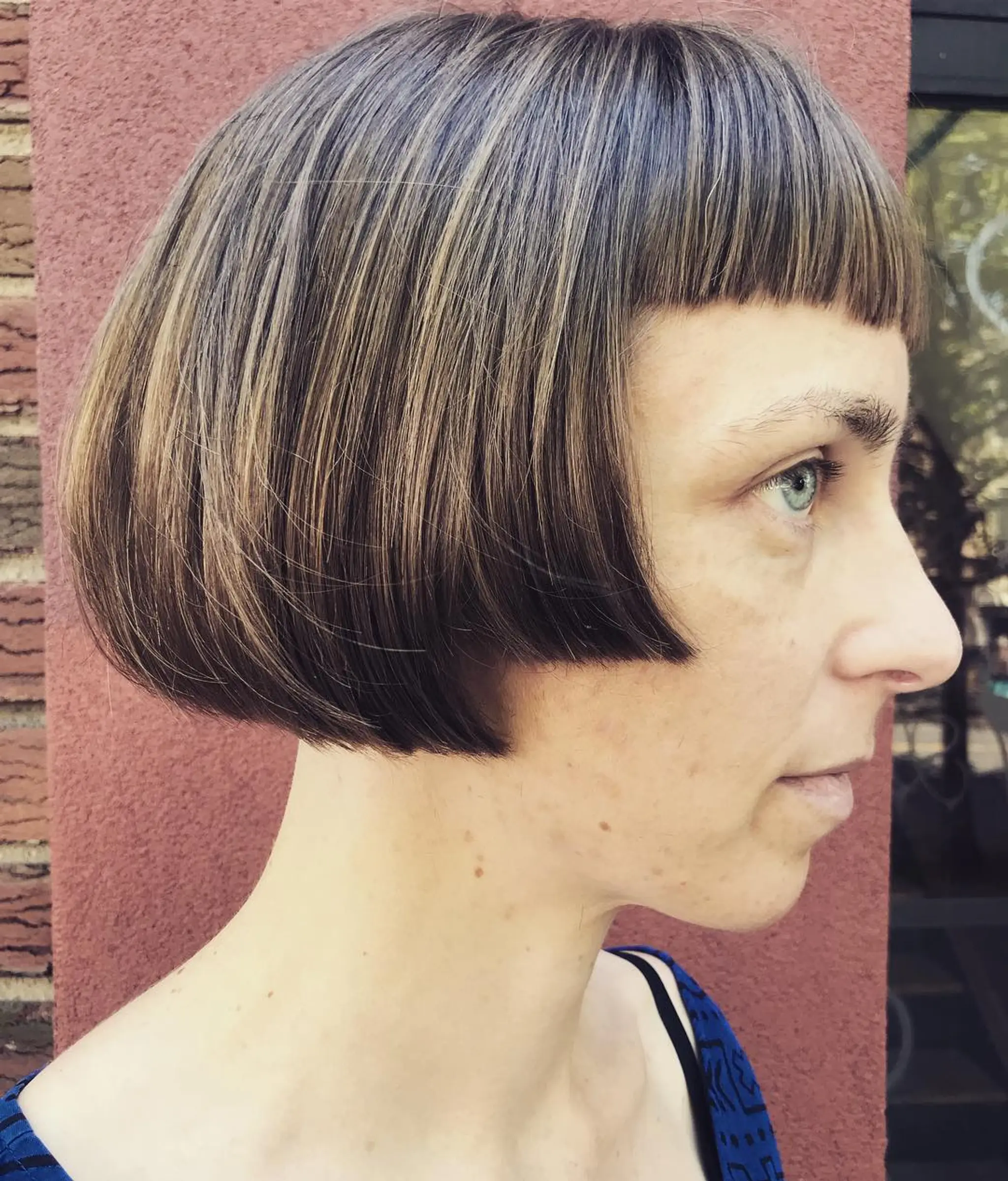 The hairstyle is a straight, smooth bob with a rounded shape and a blunt fringe, highlighted with ash tones for added depth.