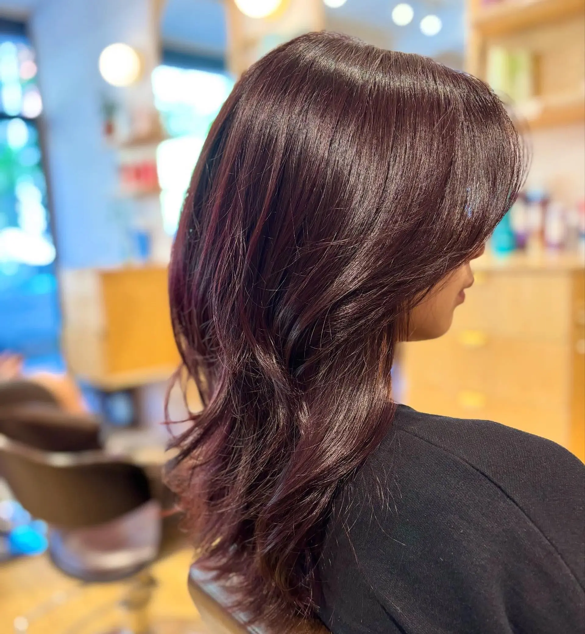 A long layered shag haircut featuring face-framing feathered layers in a deep, glossy cherry cola hue. 1