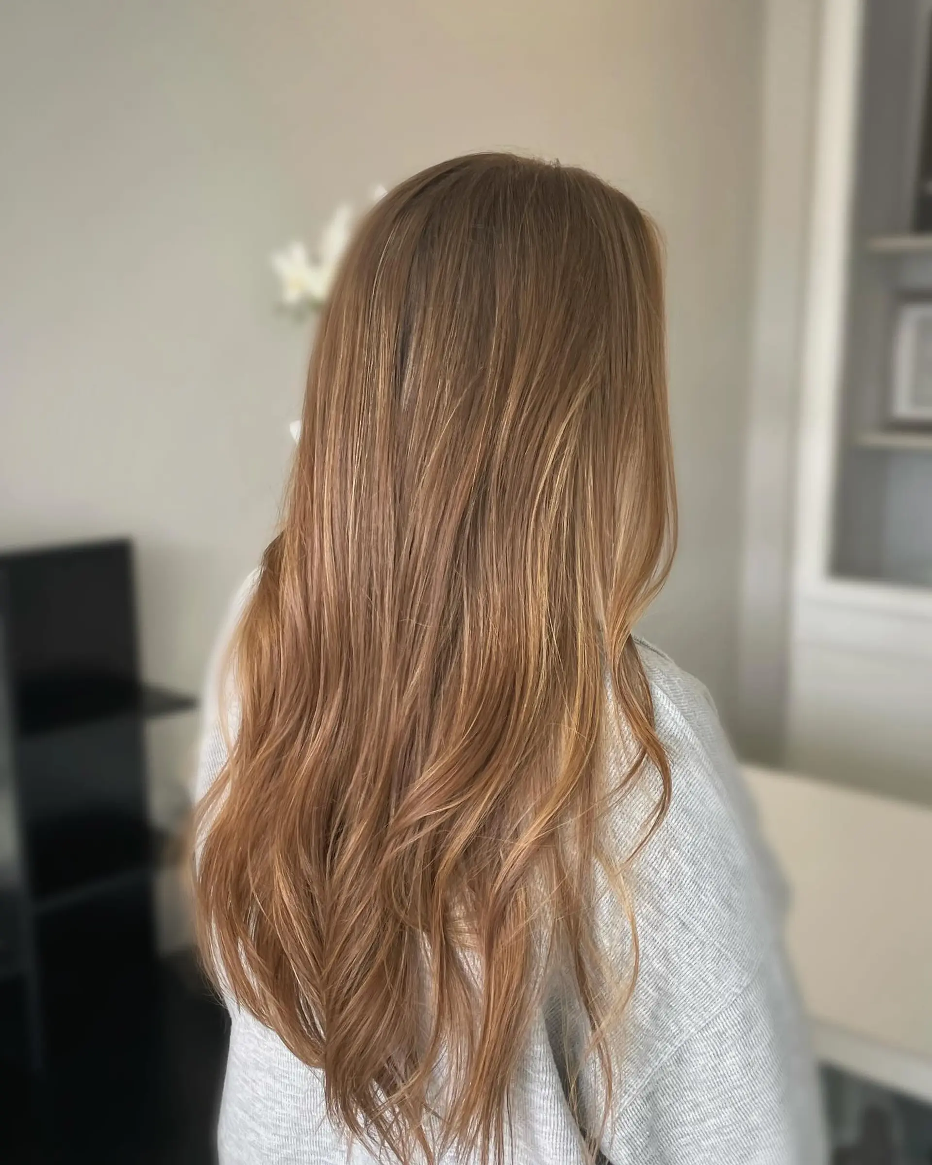 Long warm brunette hair with very fine, natural-looking honey blonde highlights styled in loose, soft waves. 1