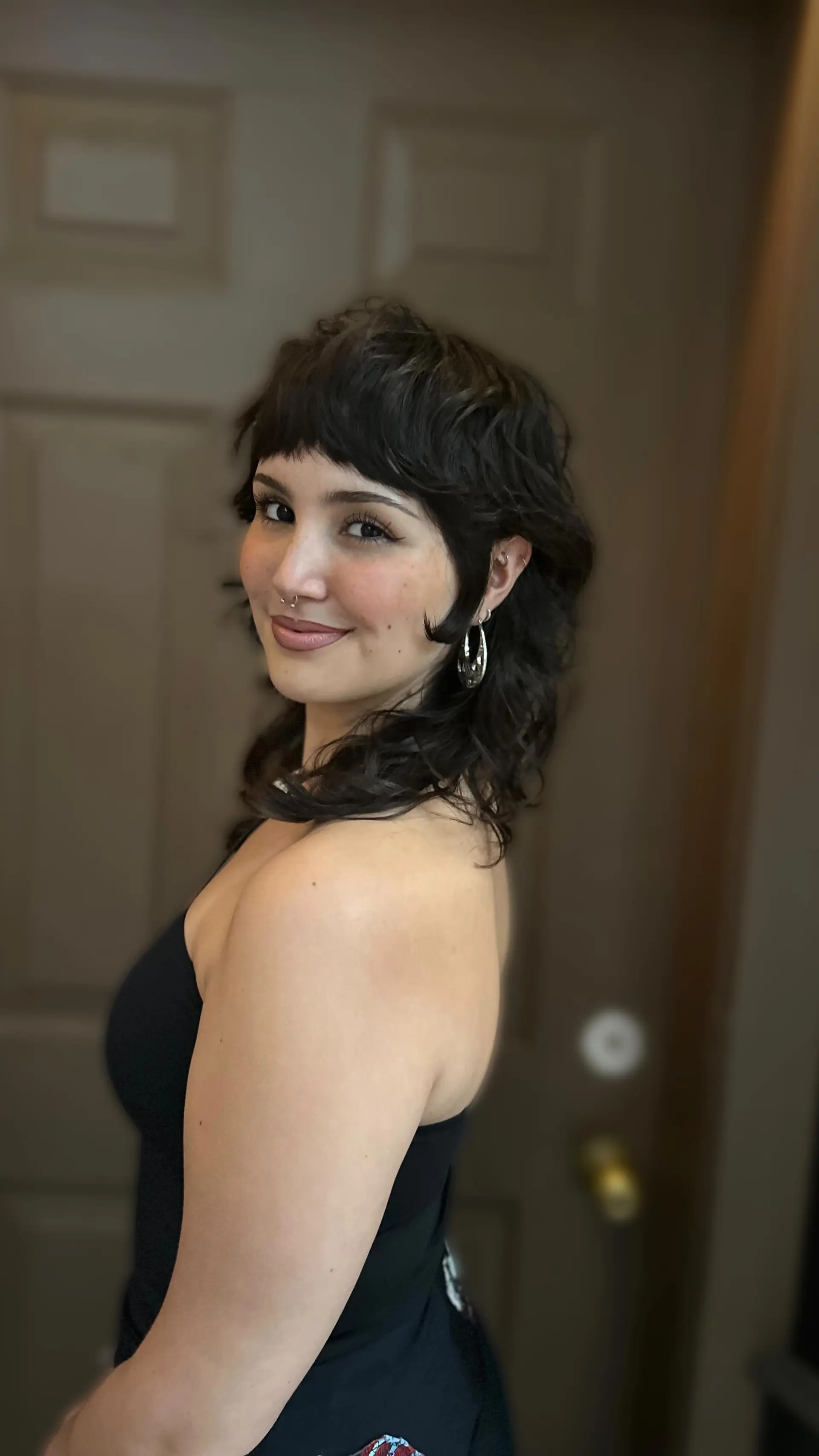 A dark brunette razor-cut shaggy mullet with textured micro bangs and soft, layered waves. 1