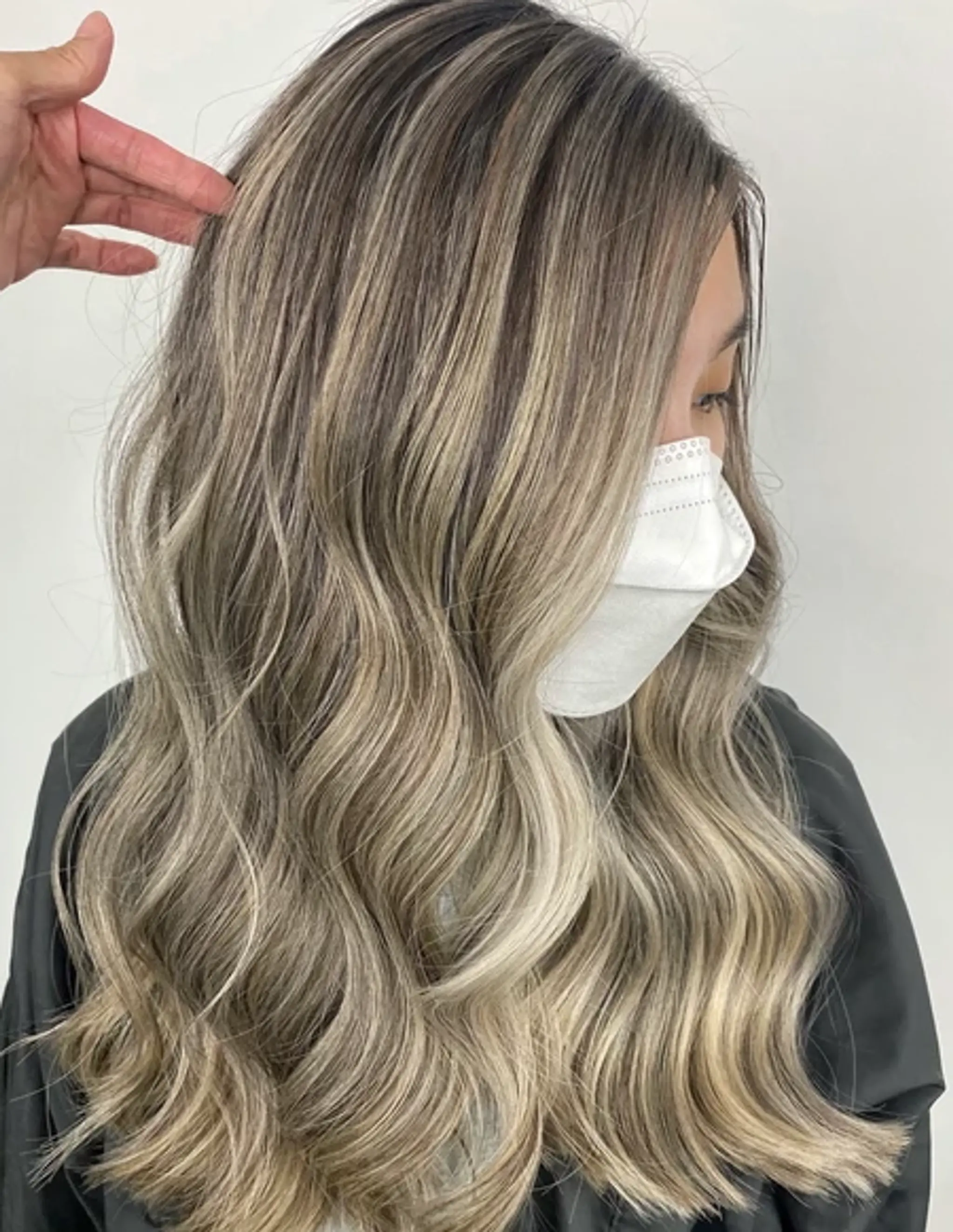 Long, wavy hair with a blend of platinum blonde, ash brown, and light brown shades, featuring a balayage technique with voluminous, soft waves and layered for movement and dimension.