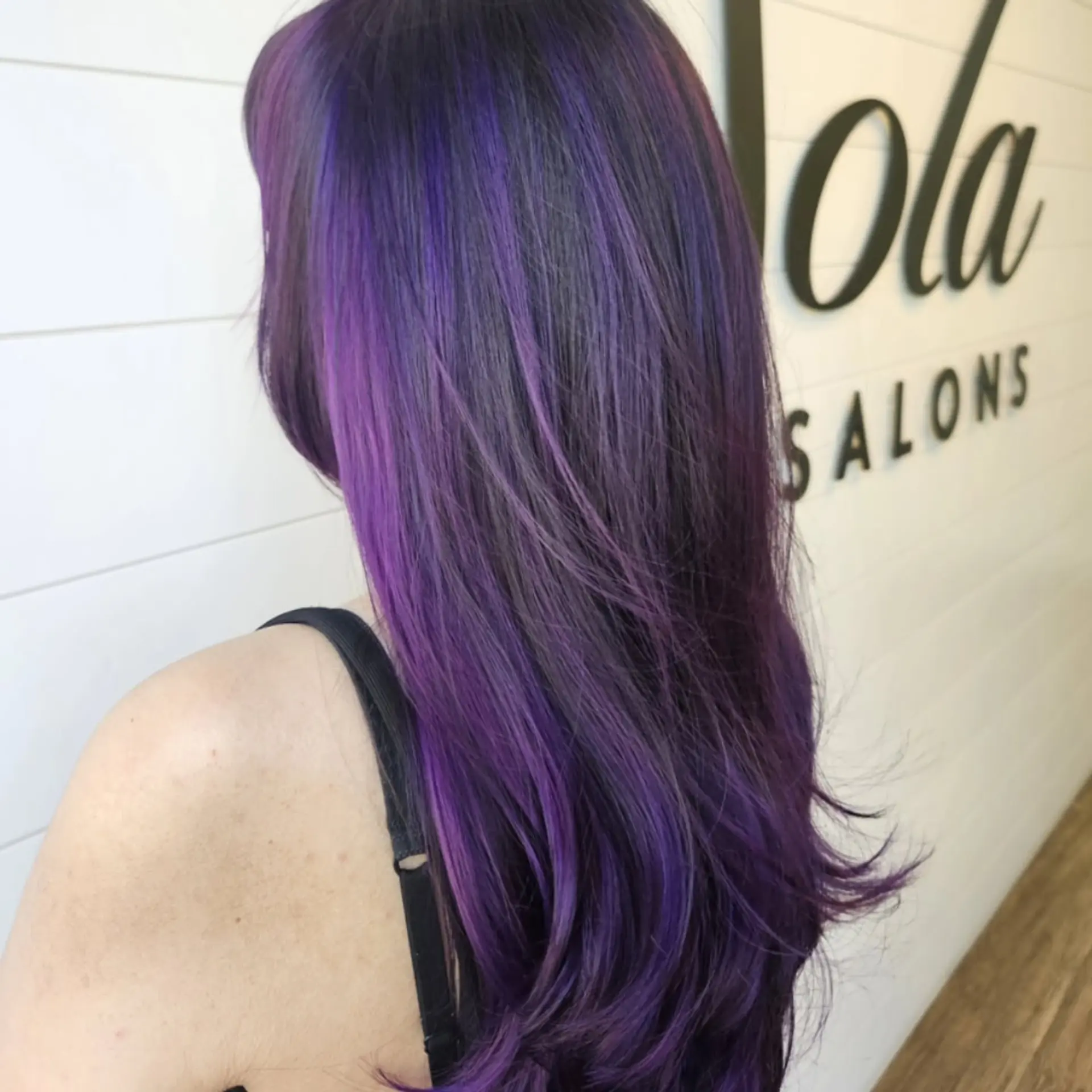 Long layered hair styled with a smooth blowout and softly flipped ends, highlighted with vibrant strokes of electric purple and deep violet. 1