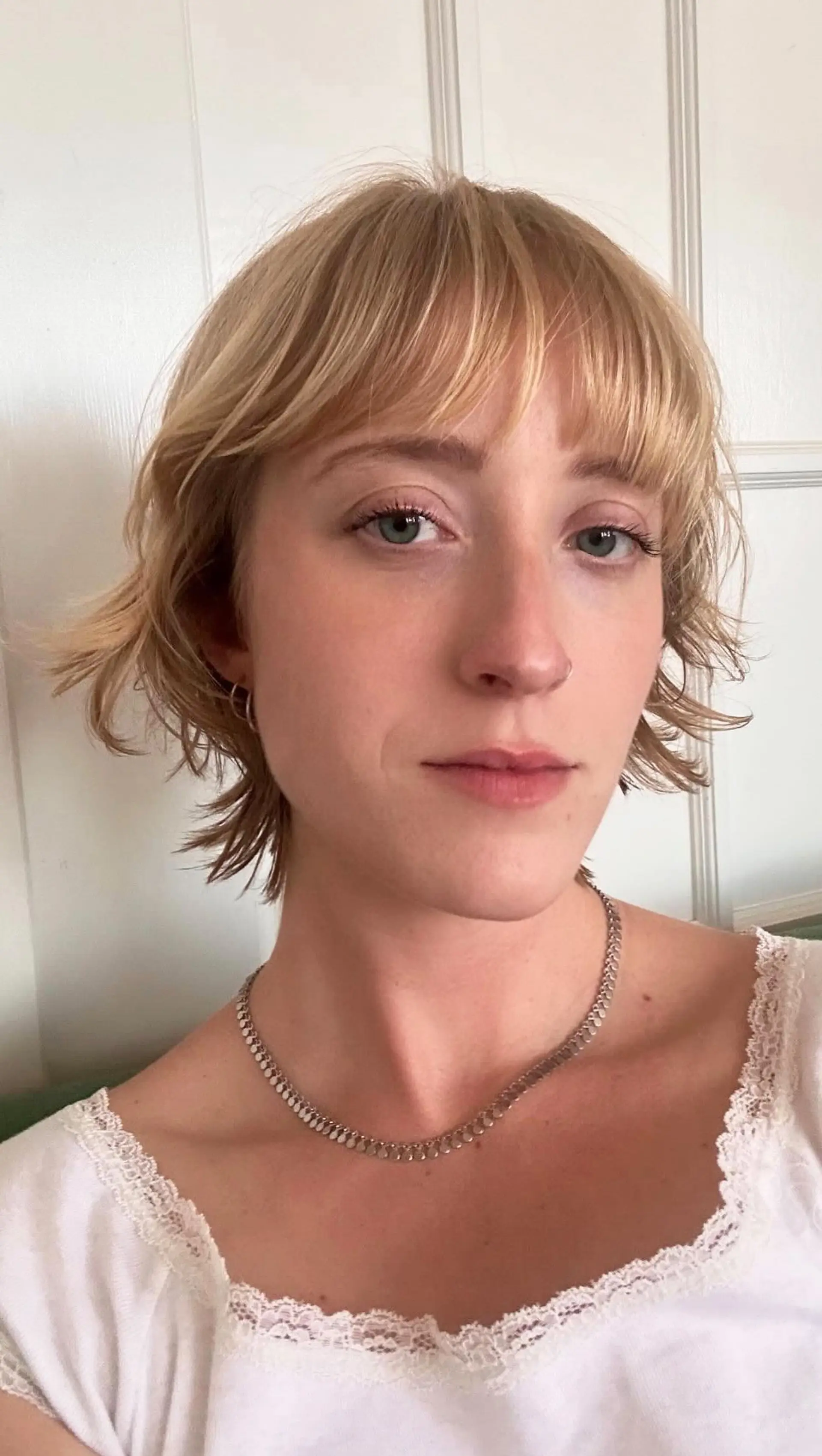A short, piecey textured bob with soft wispy bangs and flicked-out ends in a golden blonde color. 1