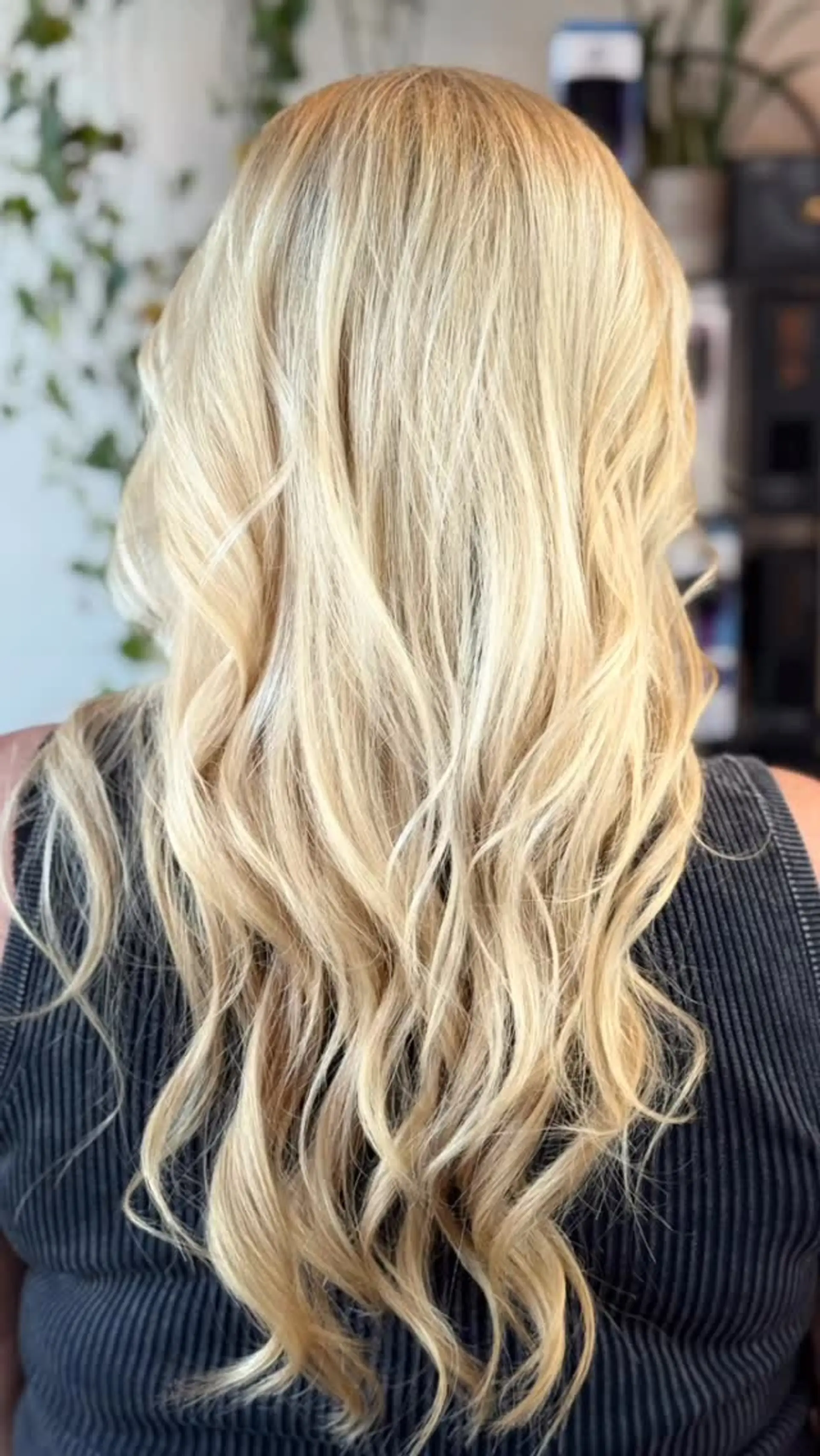 Long, bright blonde hair styled with soft, loose waves cascading down the back. 1