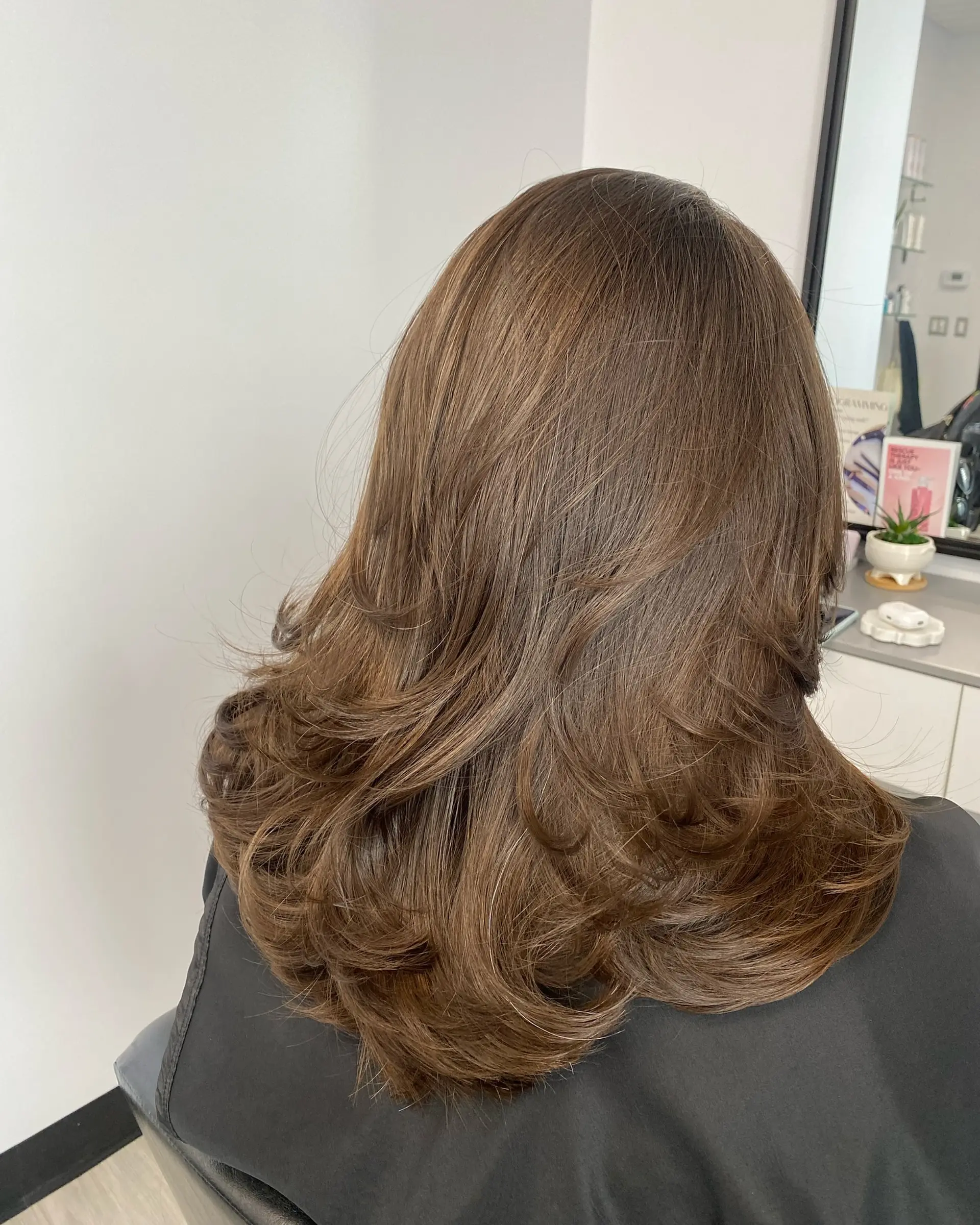 Medium-length light chestnut brown hair featuring flowing layers styled in a voluminous blowout with flipped ends. 1