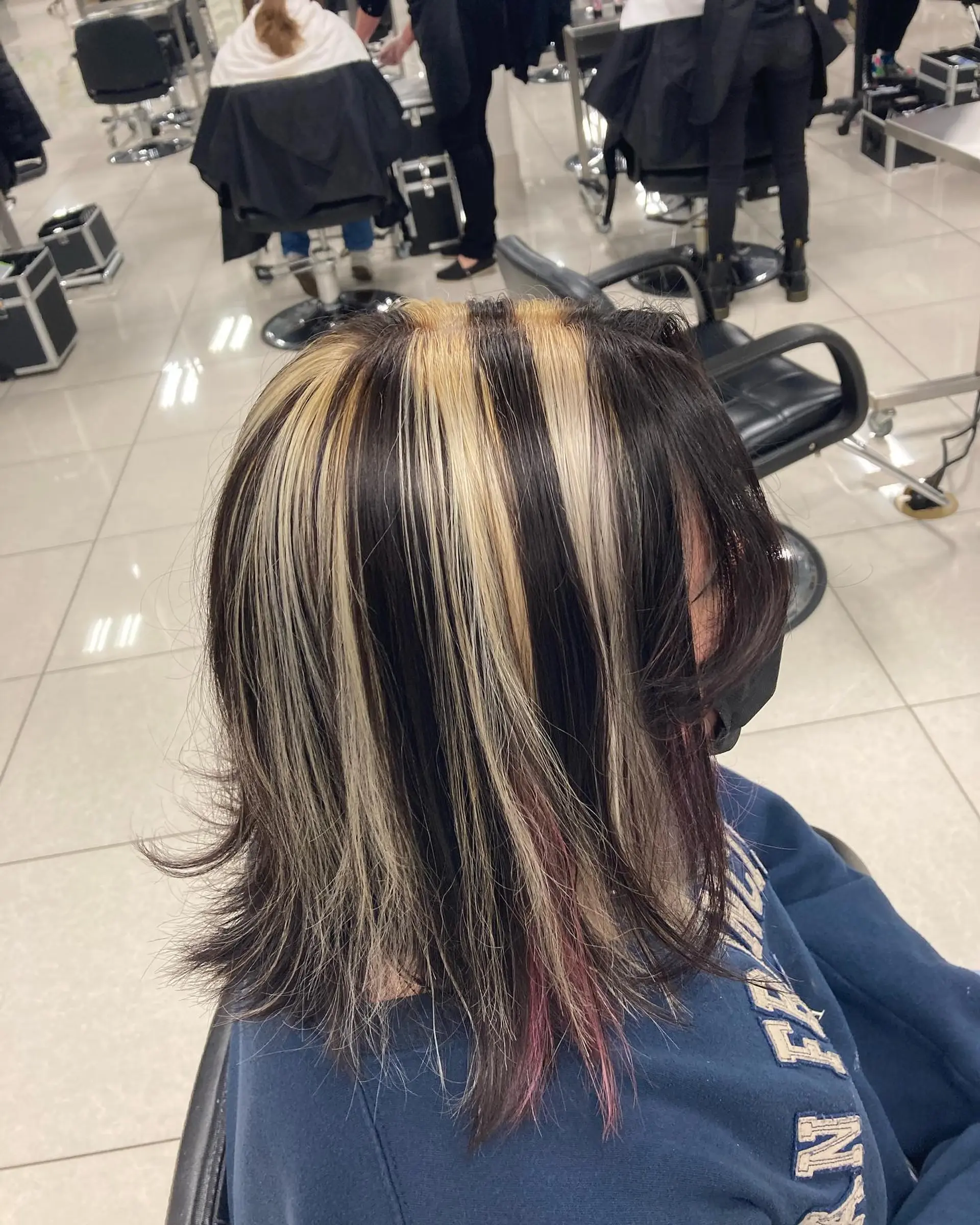 Medium-length dark hair featuring high-contrast chunky blonde highlights with layered, lightly flipped ends. 1