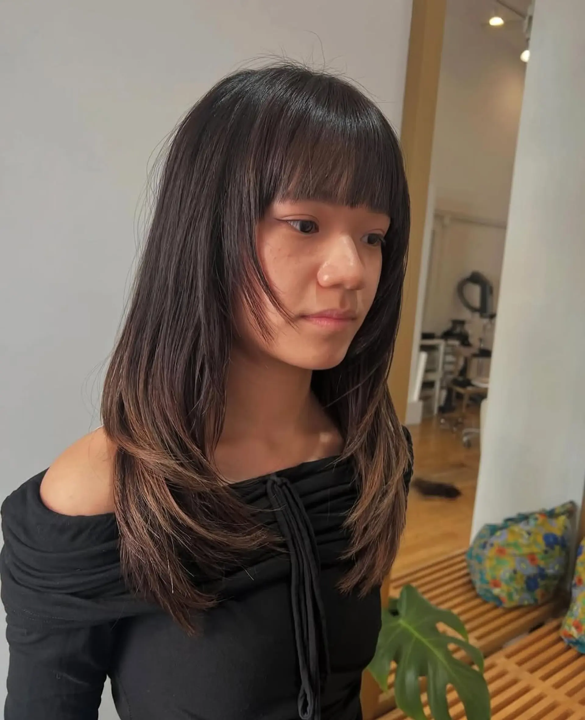 A medium-length layered haircut featuring curtain bangs with face-framing layers. 1