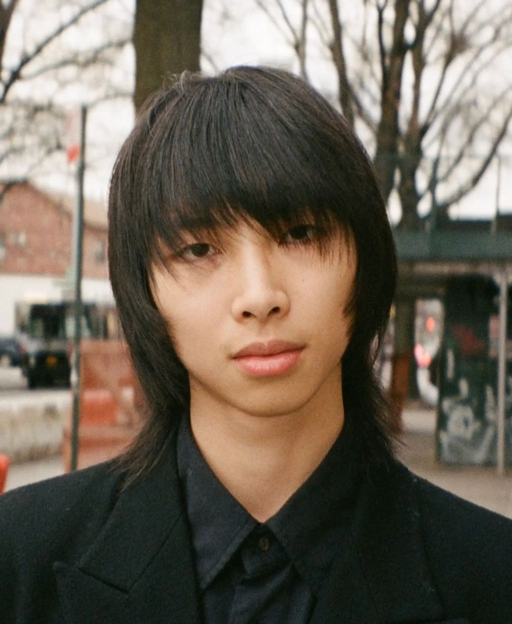 A medium-length, layered cut with a long fringe and straight texture, creating an edgy and youthful appearance.
