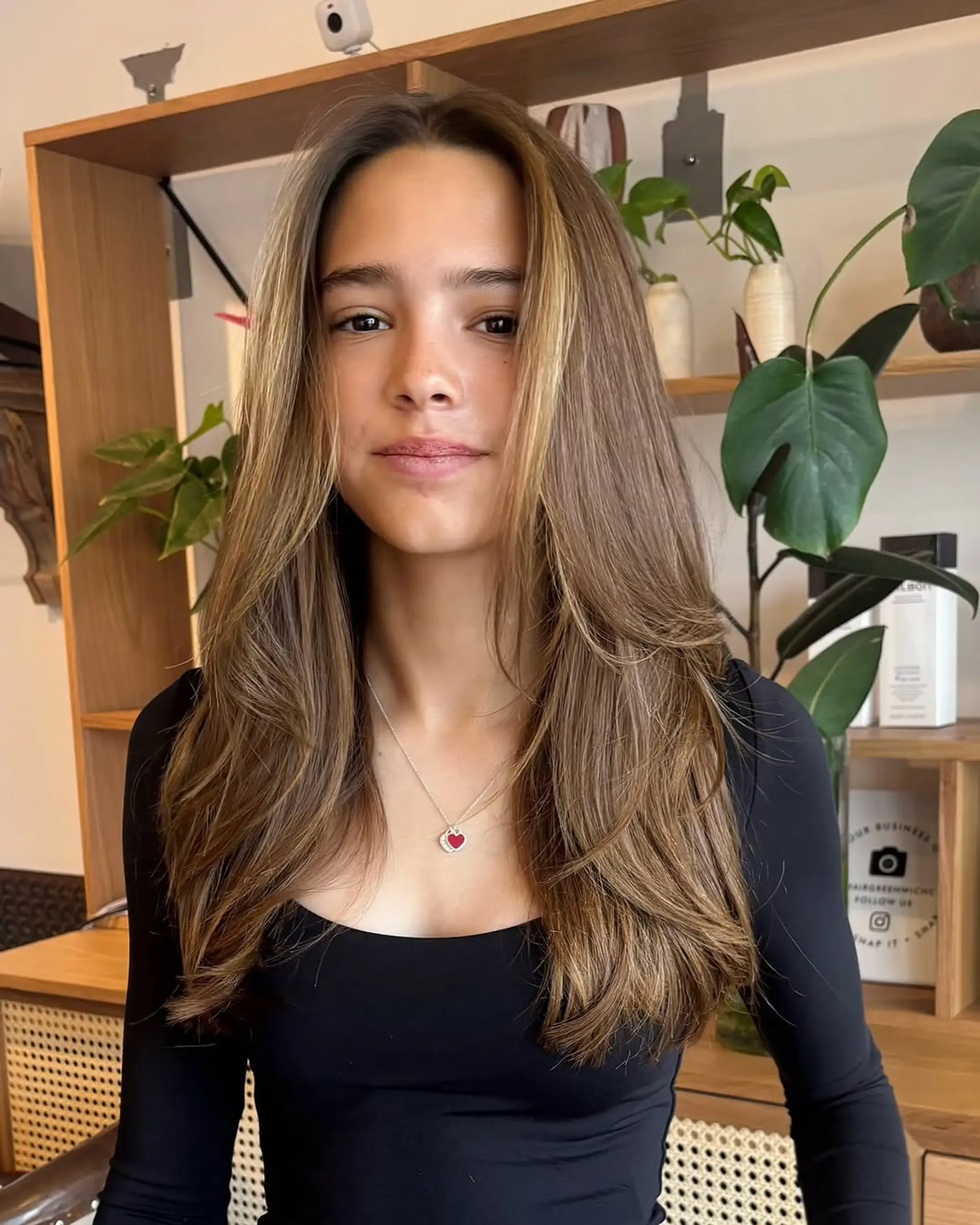 A long, layered hairstyle with face-framing layers and a subtle bronde balayage. 1