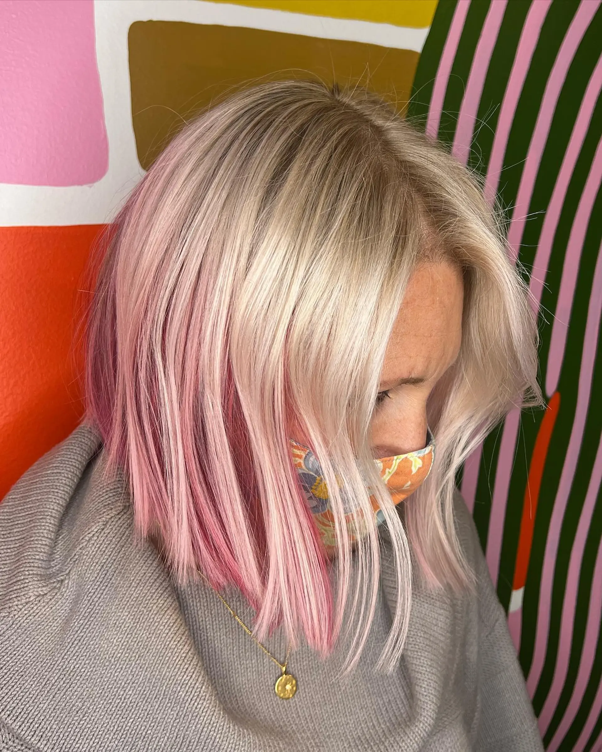 A sleek angled bob featuring a luminous platinum blonde exterior with vibrant pink peekaboo underlights. 1